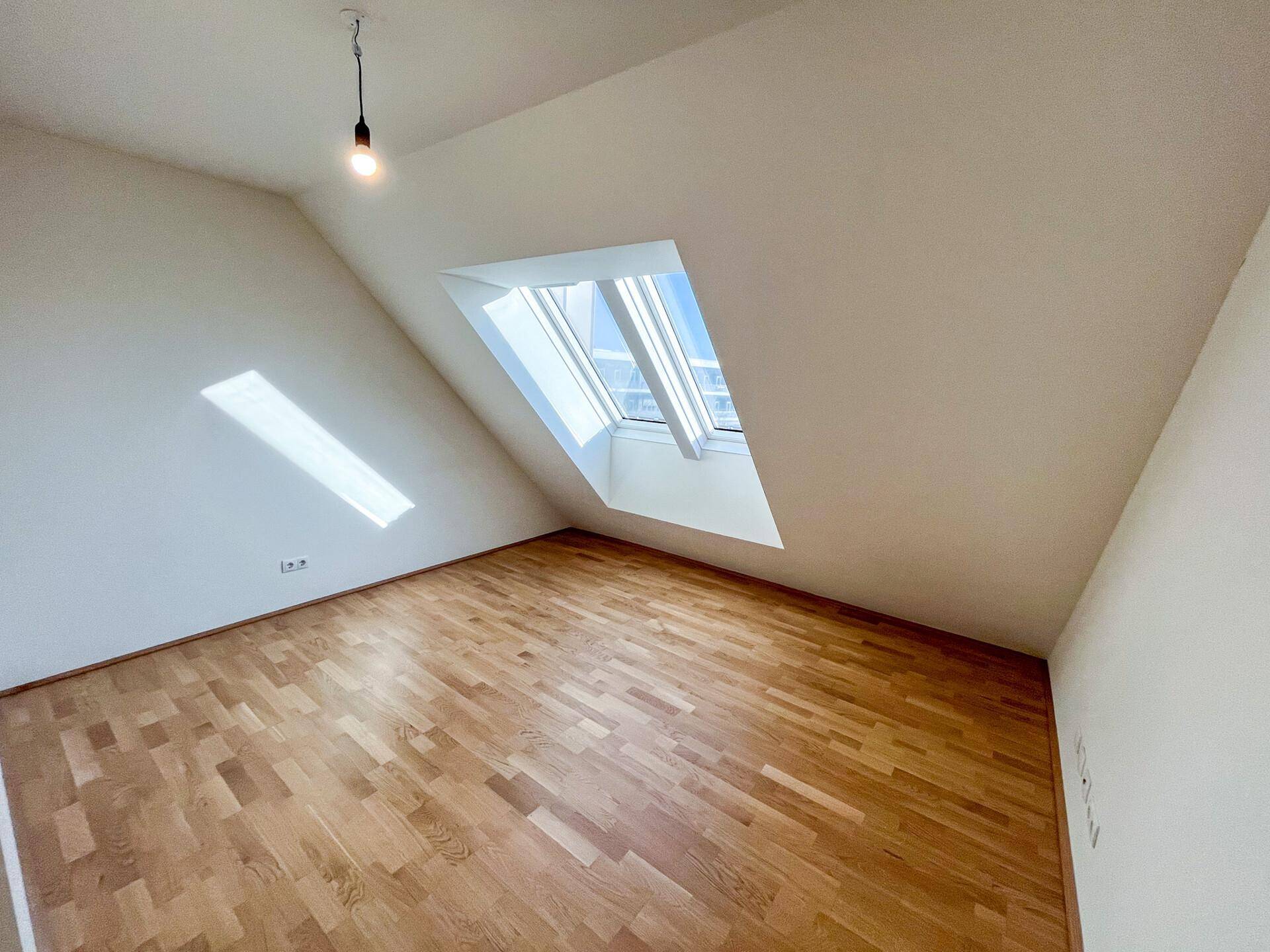 Ruhiges Zimmer mit Parkettboden und einem großen Dachfenster für viel Licht.