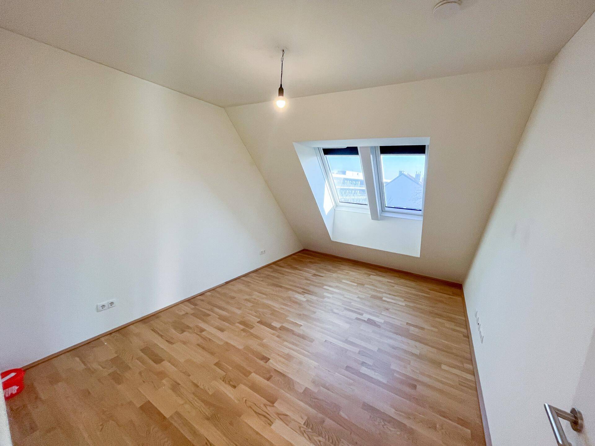 Gemütliches Zimmer mit Parkettboden und zwei Dachfenstern, ideal als Schlafzimmer.