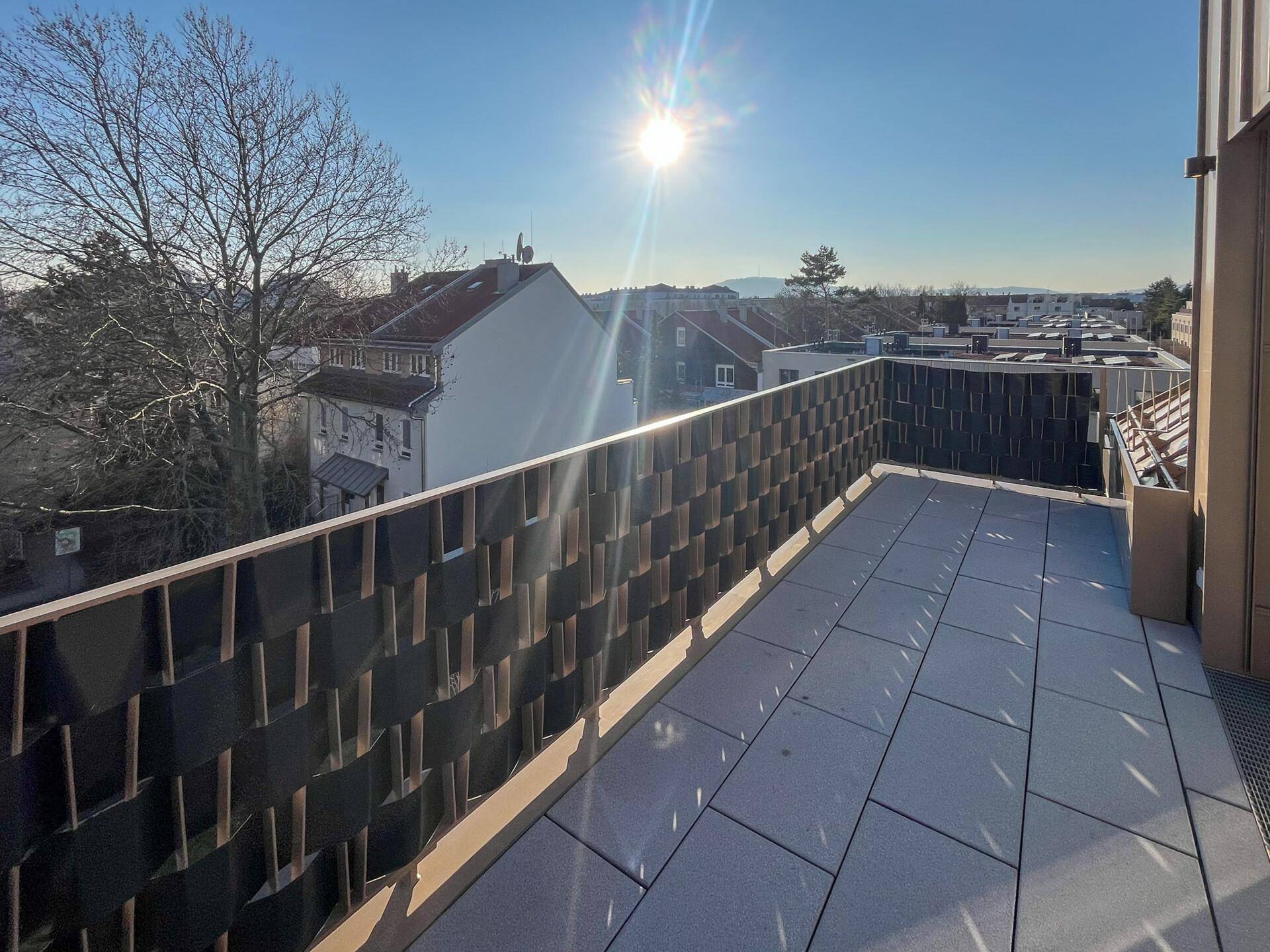 Sonniger Balkon mit modernen Fliesen und Blick auf die Umgebung.