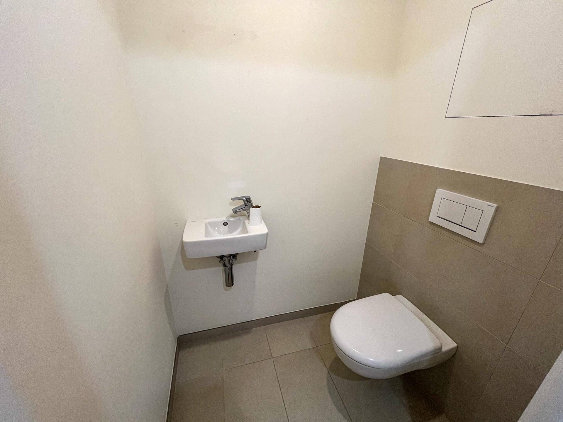 Kleines Gäste-WC mit Wand-WC und Handwaschbecken in neutralen Farben.