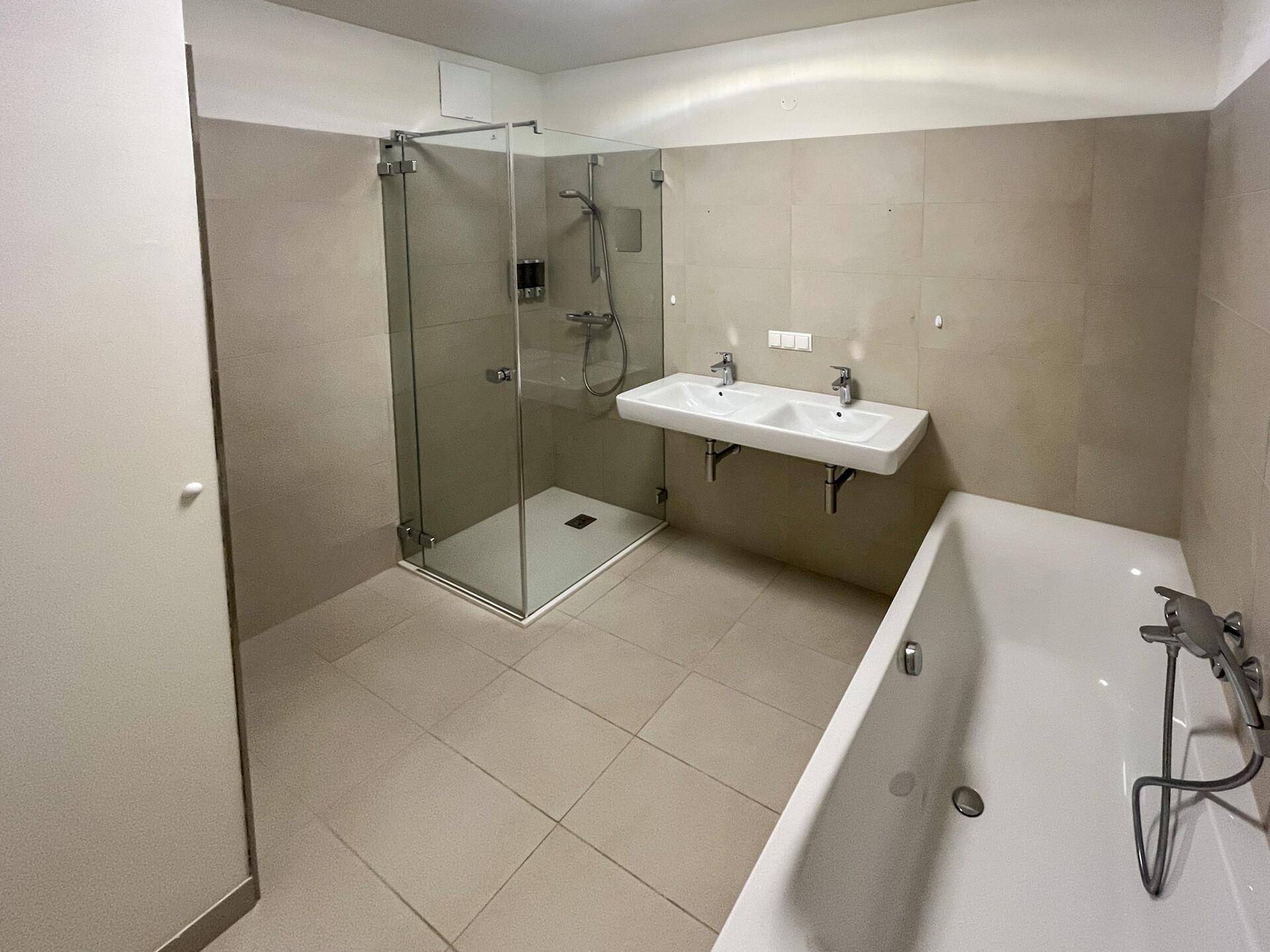 Modernes Badezimmer mit Doppelwaschbecken, großer Dusche und Badewanne.