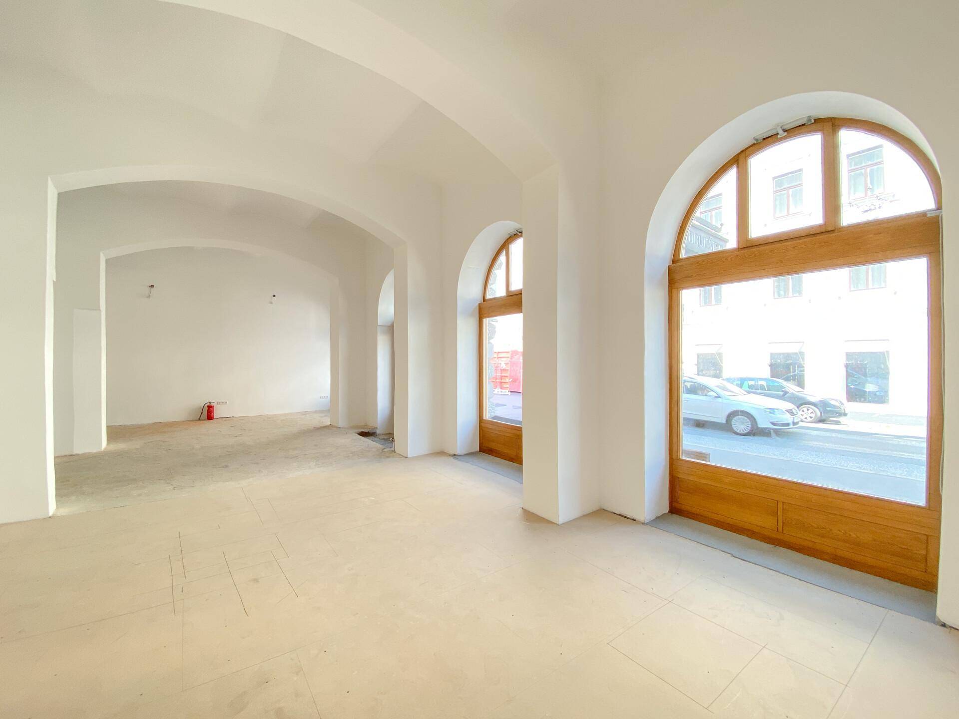 Geräumiger, heller Innenraum mit hohen Gewölbedecken und großen Rundbogenfenstern mit Blick auf die Straße.