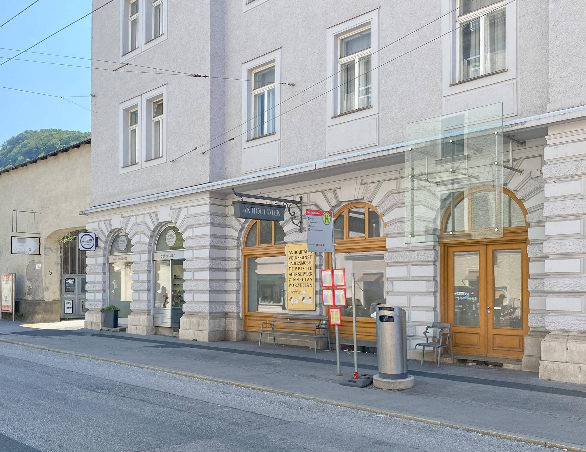 Historische Gebäudefassade mit großen Rundbogenfenstern und Holztüren an einer belebten Straße.