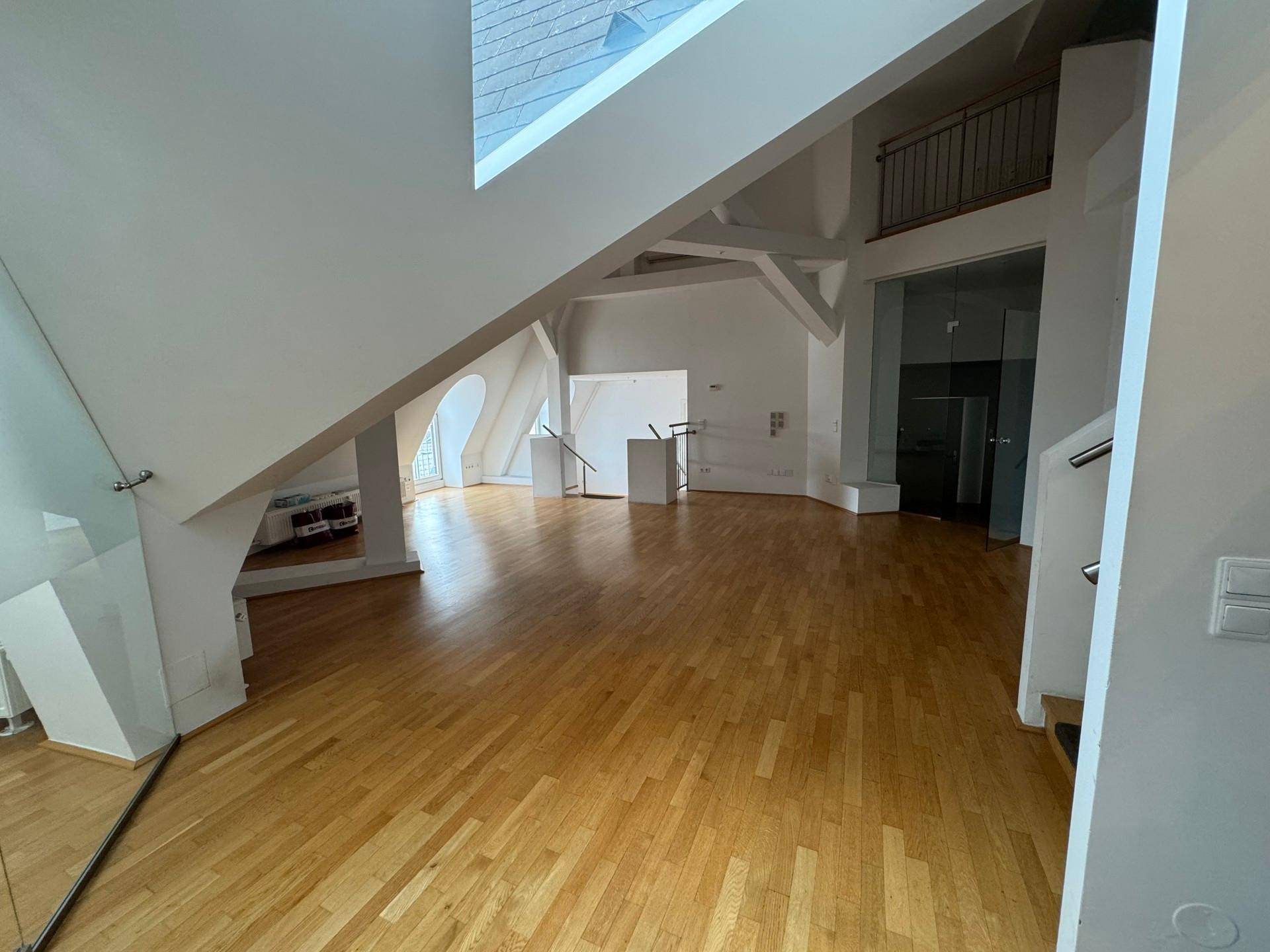 Großzügiger offener Wohnbereich mit Holzboden, hohen Decken und modernen Glaselementen.