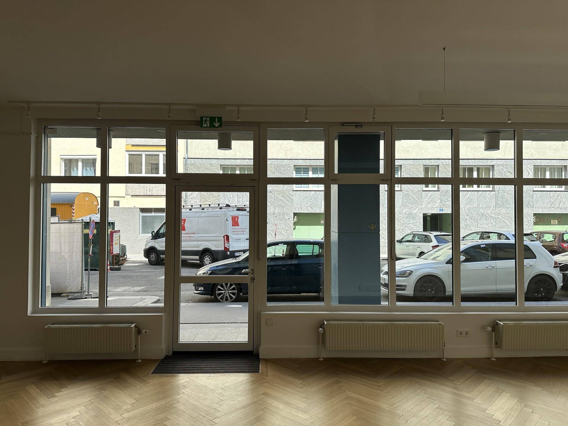 Innenansicht eines Büros mit großen Fenstern, die einen Blick auf die belebte Straße freigeben.