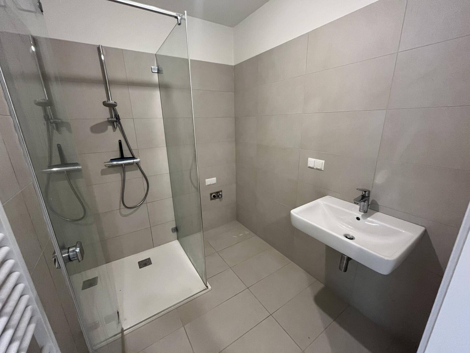 Modernes Badezimmer mit ebenerdiger Dusche, Einzelwaschbecken und hellgrauen Wand- und Bodenfliesen.