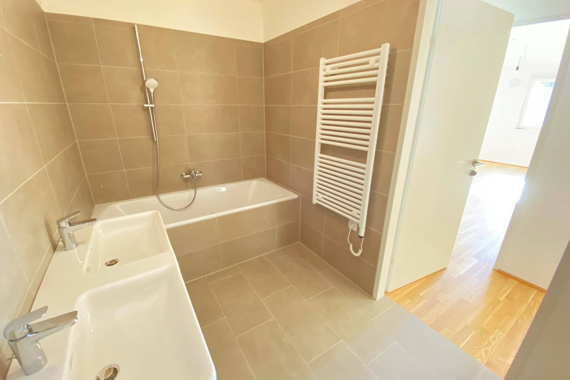 Modernes Badezimmer mit Badewanne, Doppelwaschbecken und beheiztem Handtuchhalter.