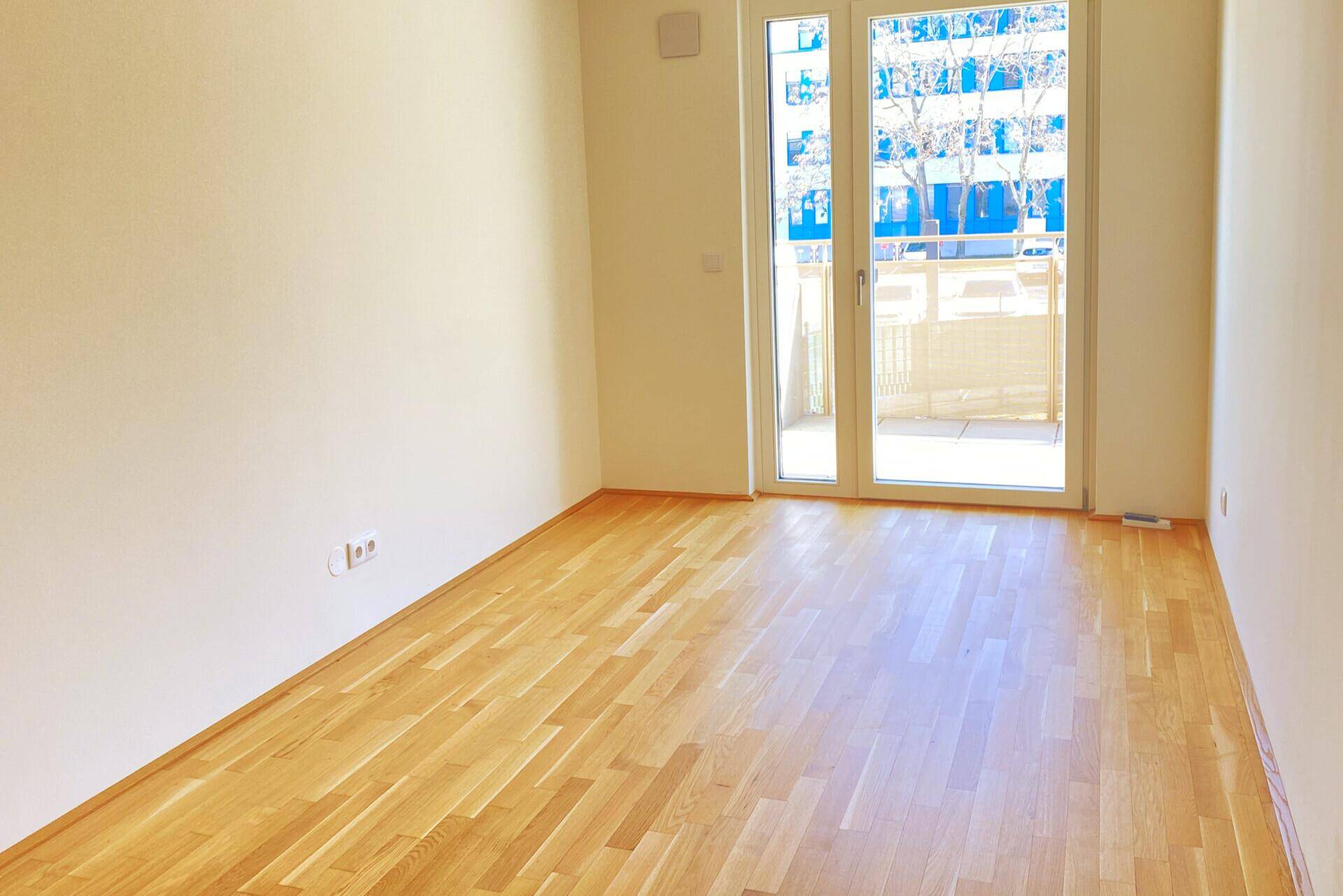 Sonniges Zimmer mit Parkettboden und Balkonzugang, ideal als Schlafzimmer.