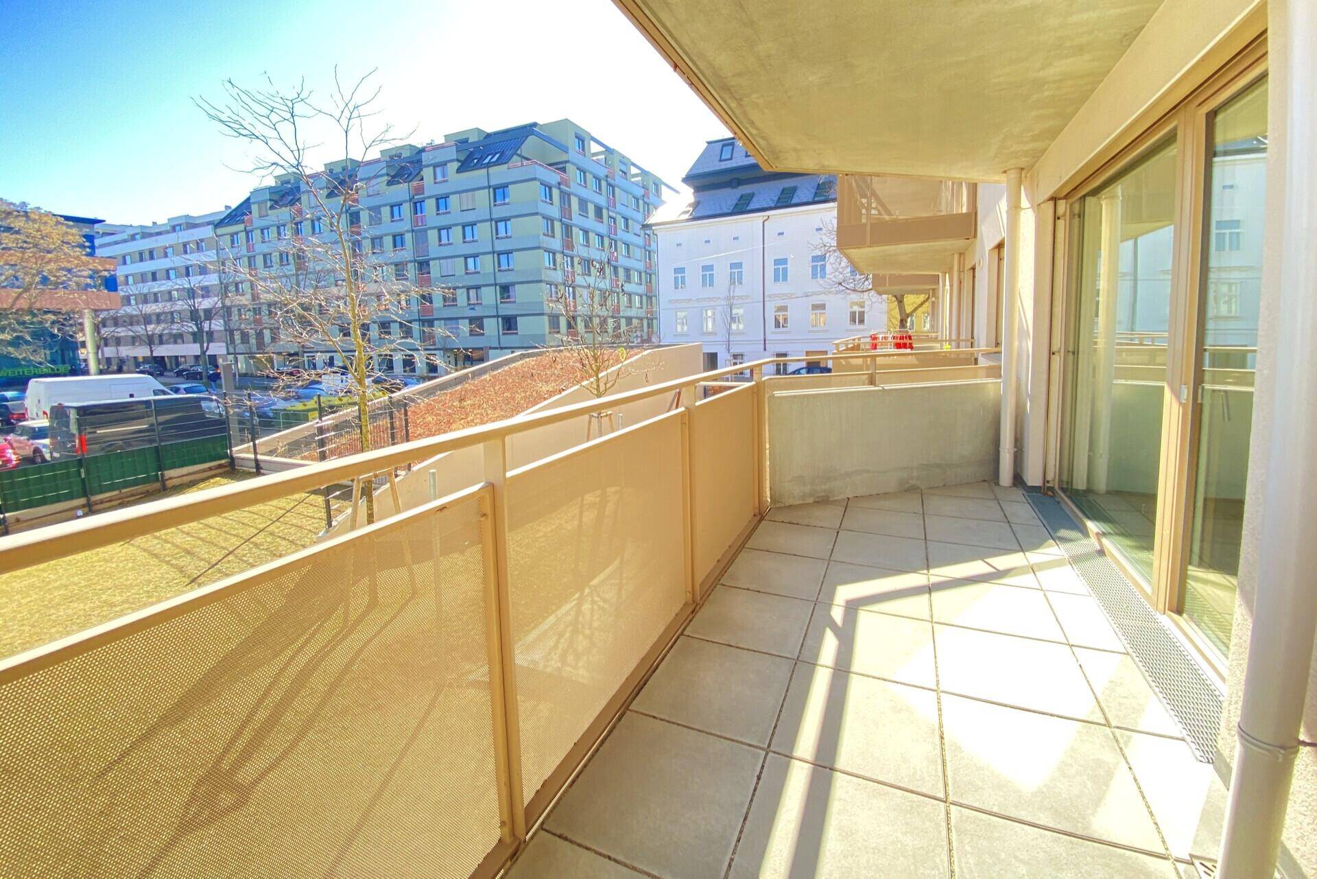 Geräumiger Balkon mit Fliesenboden und Blick auf die umliegenden Gebäude.