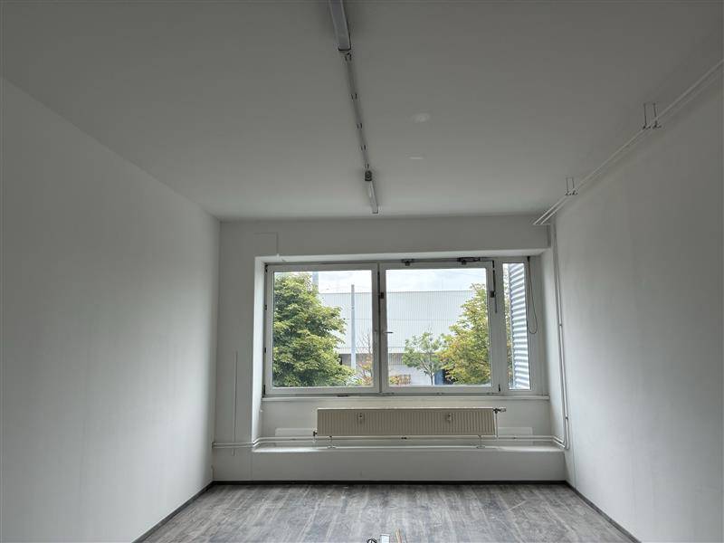 Kleinerer Büroraum mit Fenster, Heizkörper und dunklem Bodenbelag, bereit zur individuellen Gestaltung.