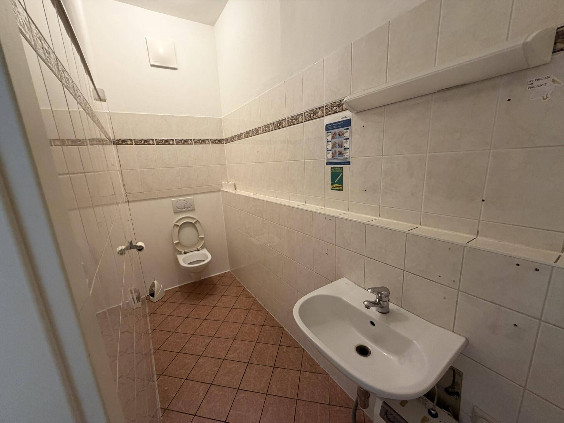 Kleiner Toilettenraum mit gefliesten Wänden und Boden, ausgestattet mit WC und Waschbecken.