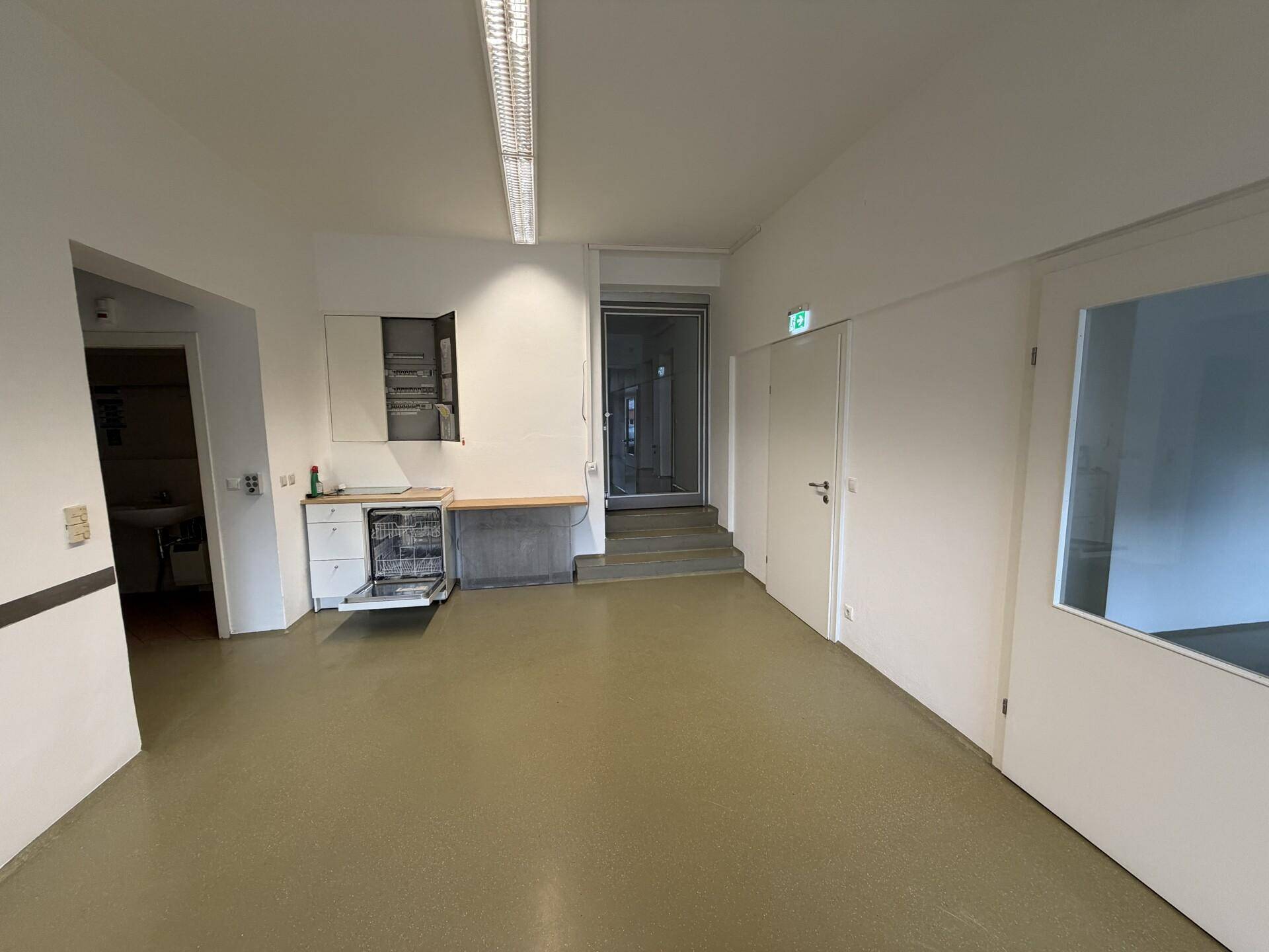 Geräumiger Flur oder offener Bereich mit Spülmaschine, Treppenaufgang und heller Beleuchtung.