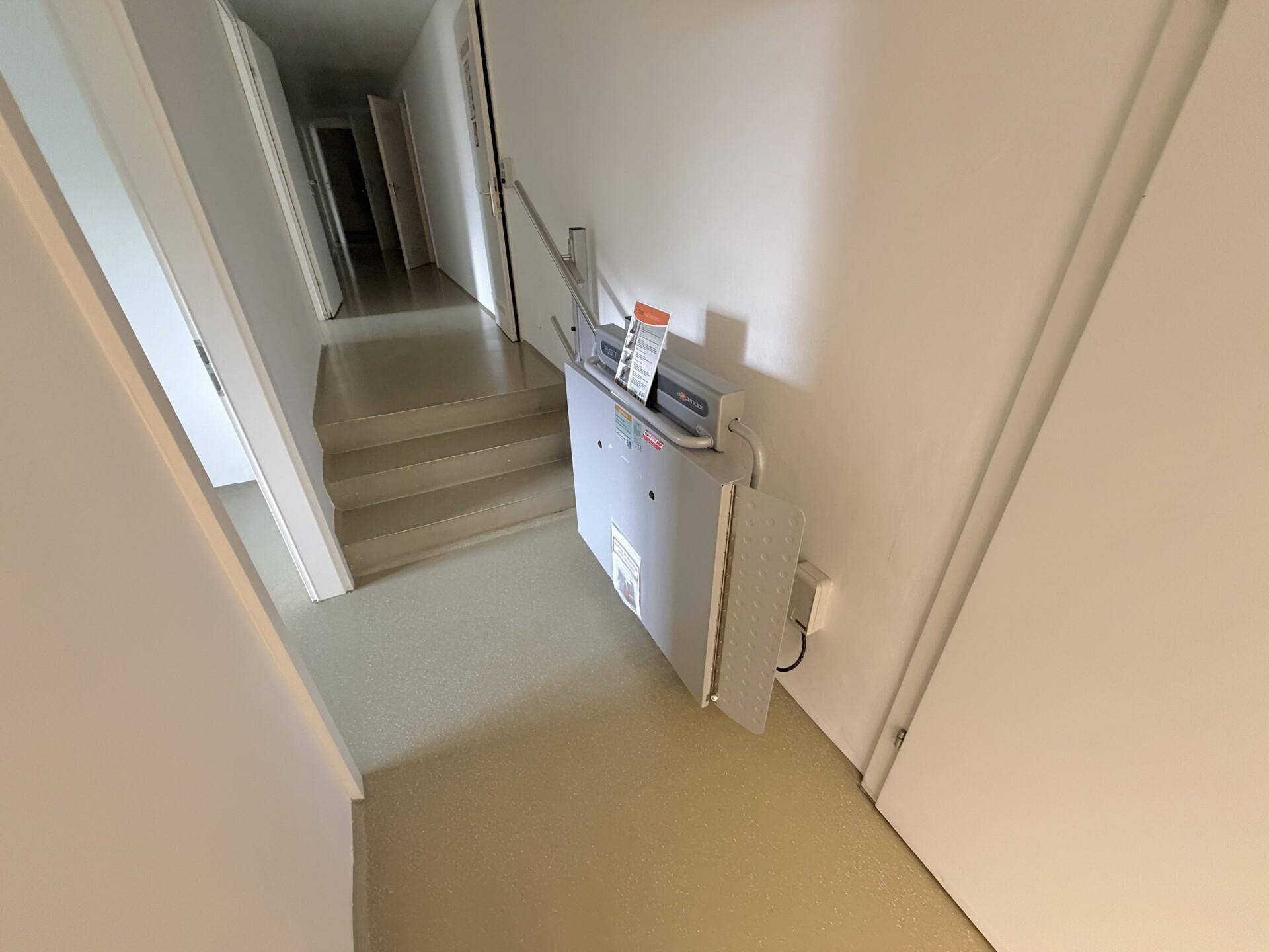 Flur mit Treppenlift für Barrierefreiheit, der zu einem oberen Stockwerk führt.