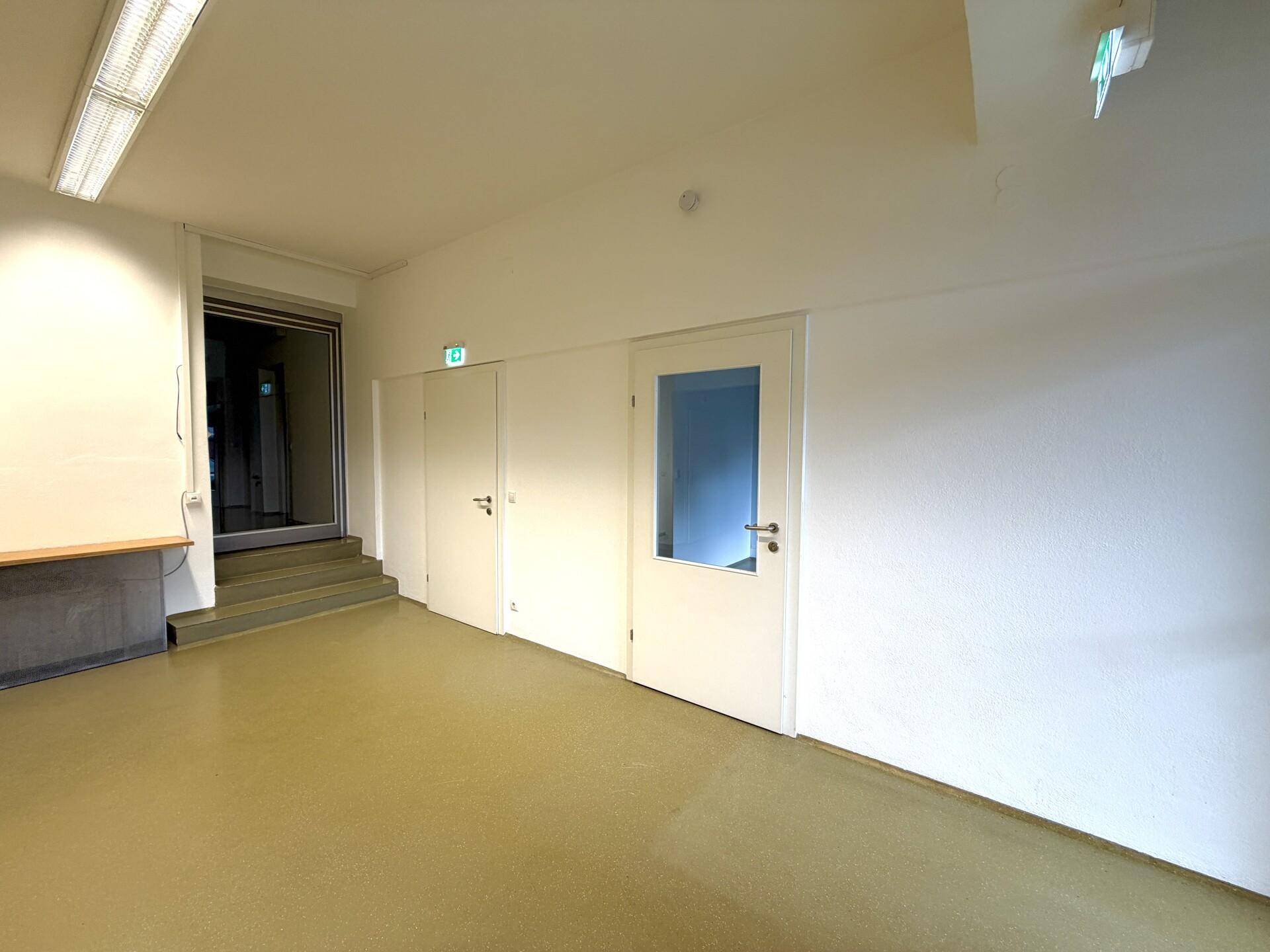 Heller Flur oder offener Bereich mit Treppenaufgang und Zugang zu weiteren Räumen.
