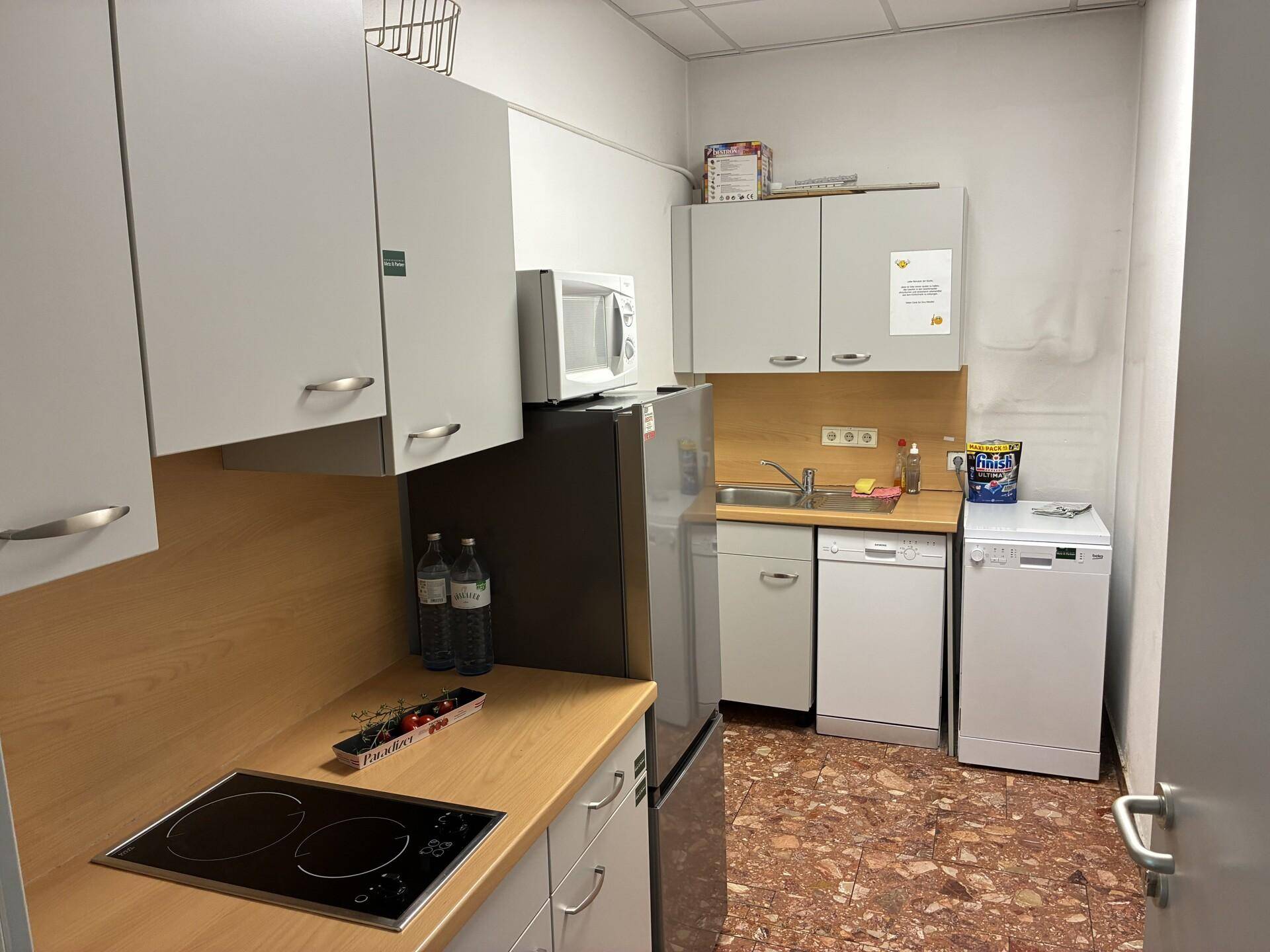 Kleine Küchenzeile mit hellen Schränken, Holz-Arbeitsplatten und integrierten Geräten.