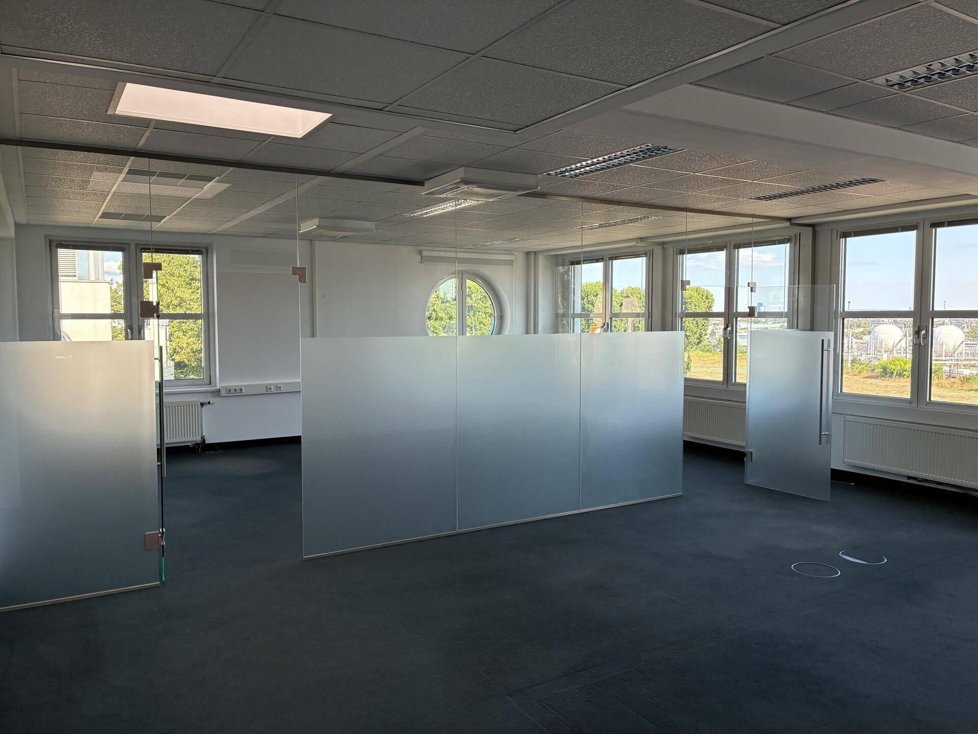 Großes Büro mit modernen Glasabtrennungen, die für eine offene und helle Arbeitsumgebung sorgen.