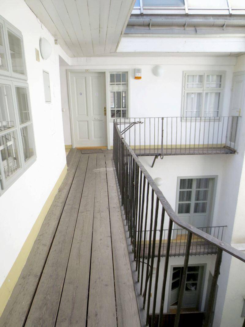 Historischer Innenhof eines Altbaus mit Holzstegen und Geländern, der zu den Wohnungseingängen führt.