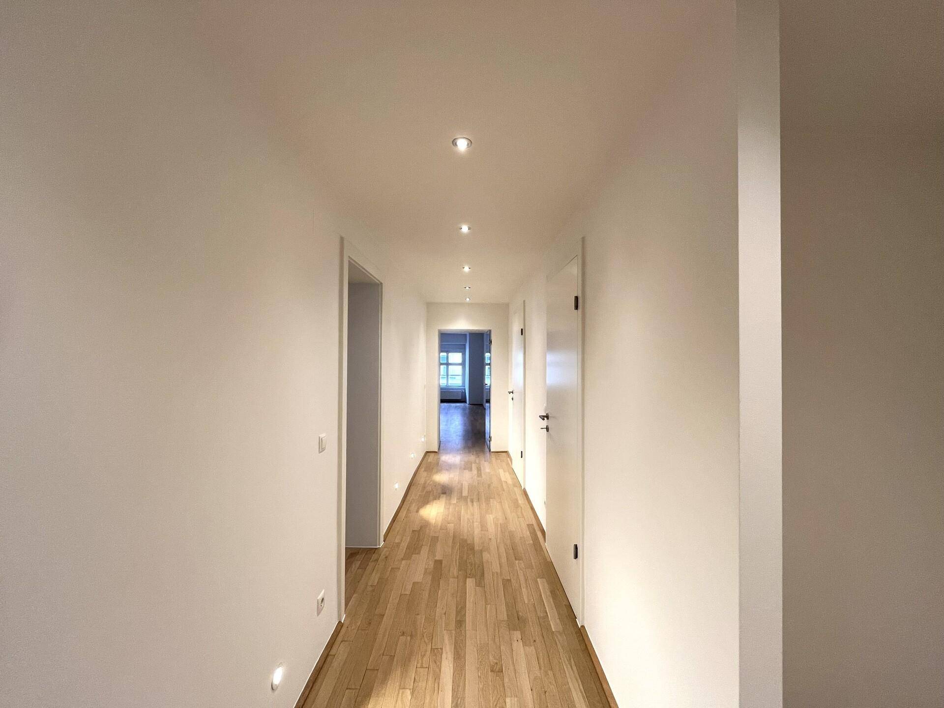 Langer, heller Flur mit Parkettboden und mehreren Türen, der die verschiedenen Räume der Wohnung verbindet.