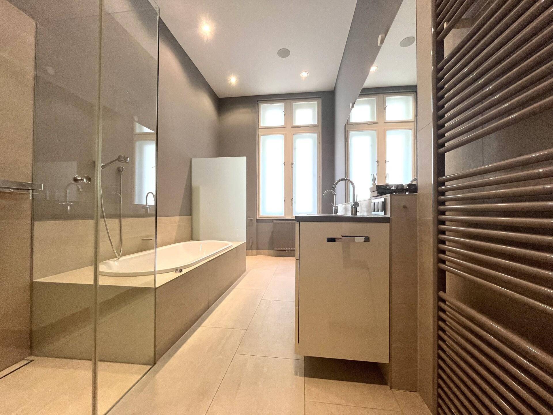 Modernes Badezimmer mit Badewanne, begehbarer Dusche, Einzelwaschbecken und beheiztem Handtuchhalter.