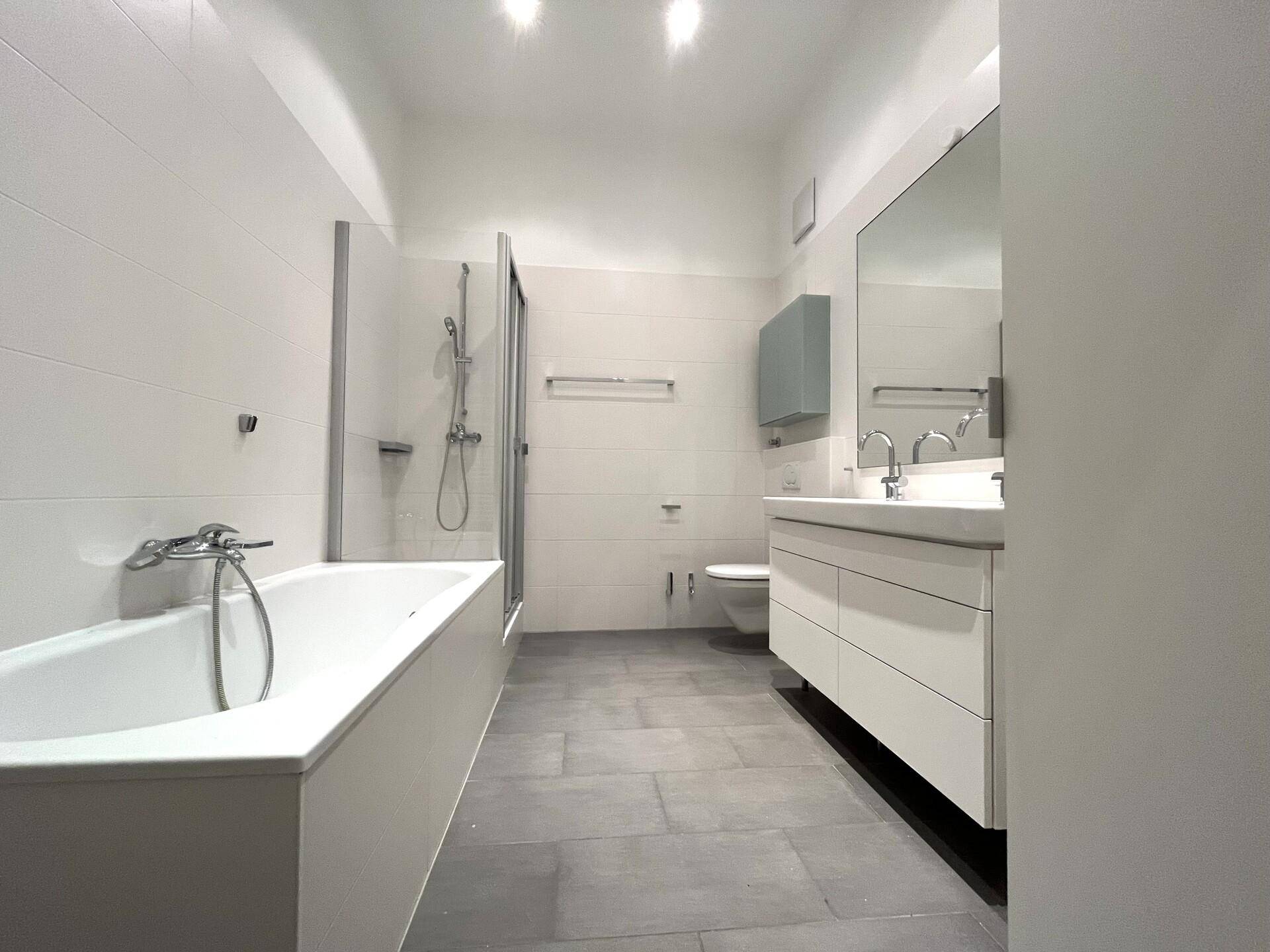 Modernes Badezimmer mit Badewanne, Dusche, Einzelwaschbecken und wandhängendem WC.