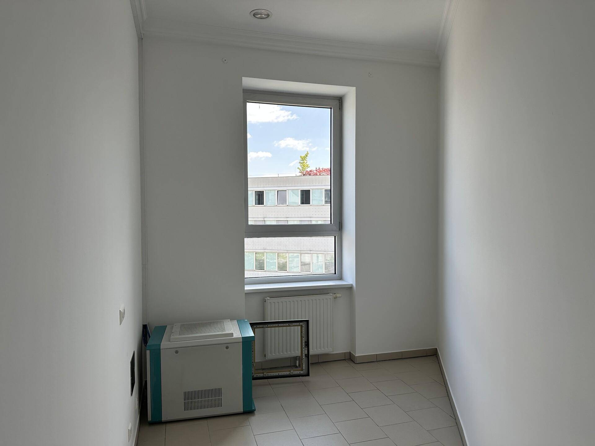 Kleiner Raum mit Fenster, Fliesenboden und einem Gerät, geeignet als Lager oder kleines Büro.
