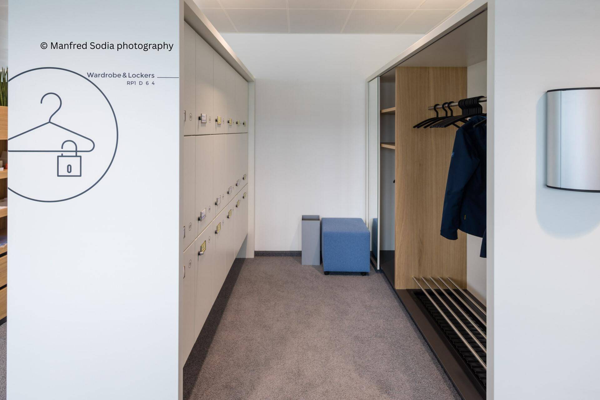 Moderner Umkleidebereich mit Schließfächern, einer Sitzbank und einer offenen Garderobe.
