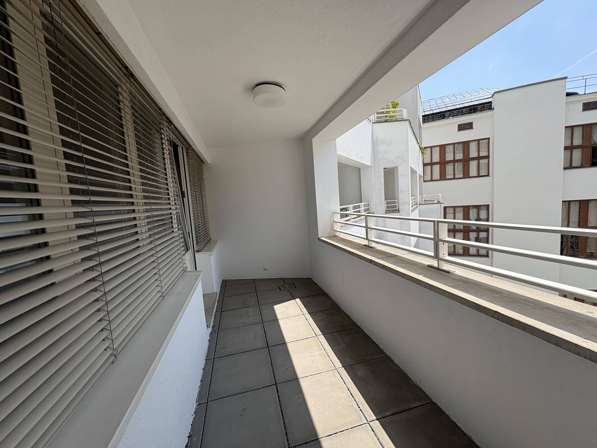 Schmaler Balkon mit Fliesenboden und Blick auf die umliegenden Gebäude.