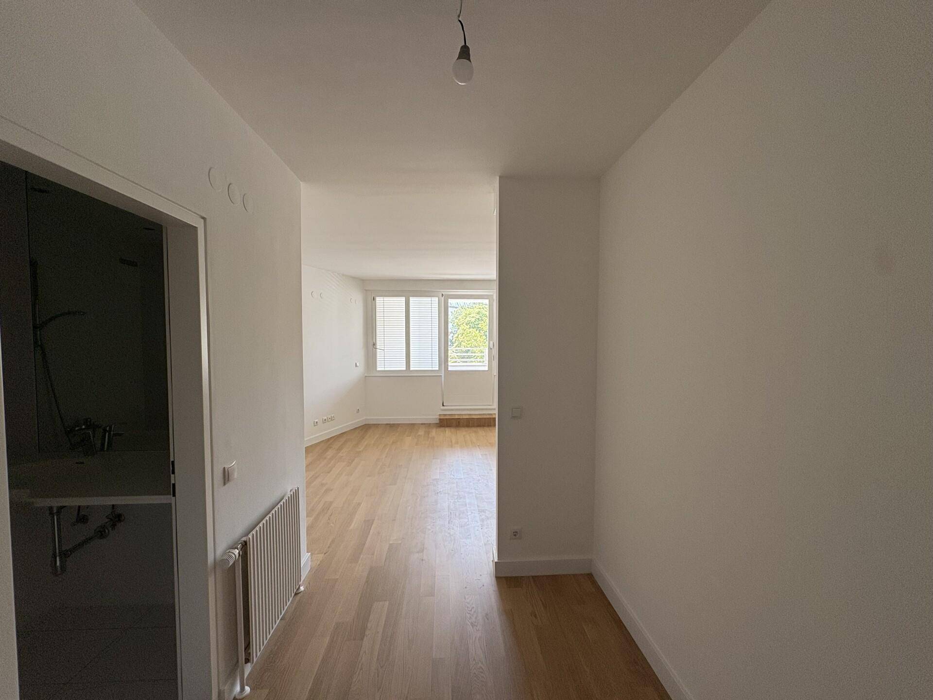 Heller Flur mit Parkettboden, der zum offenen Wohnbereich der Wohnung führt.