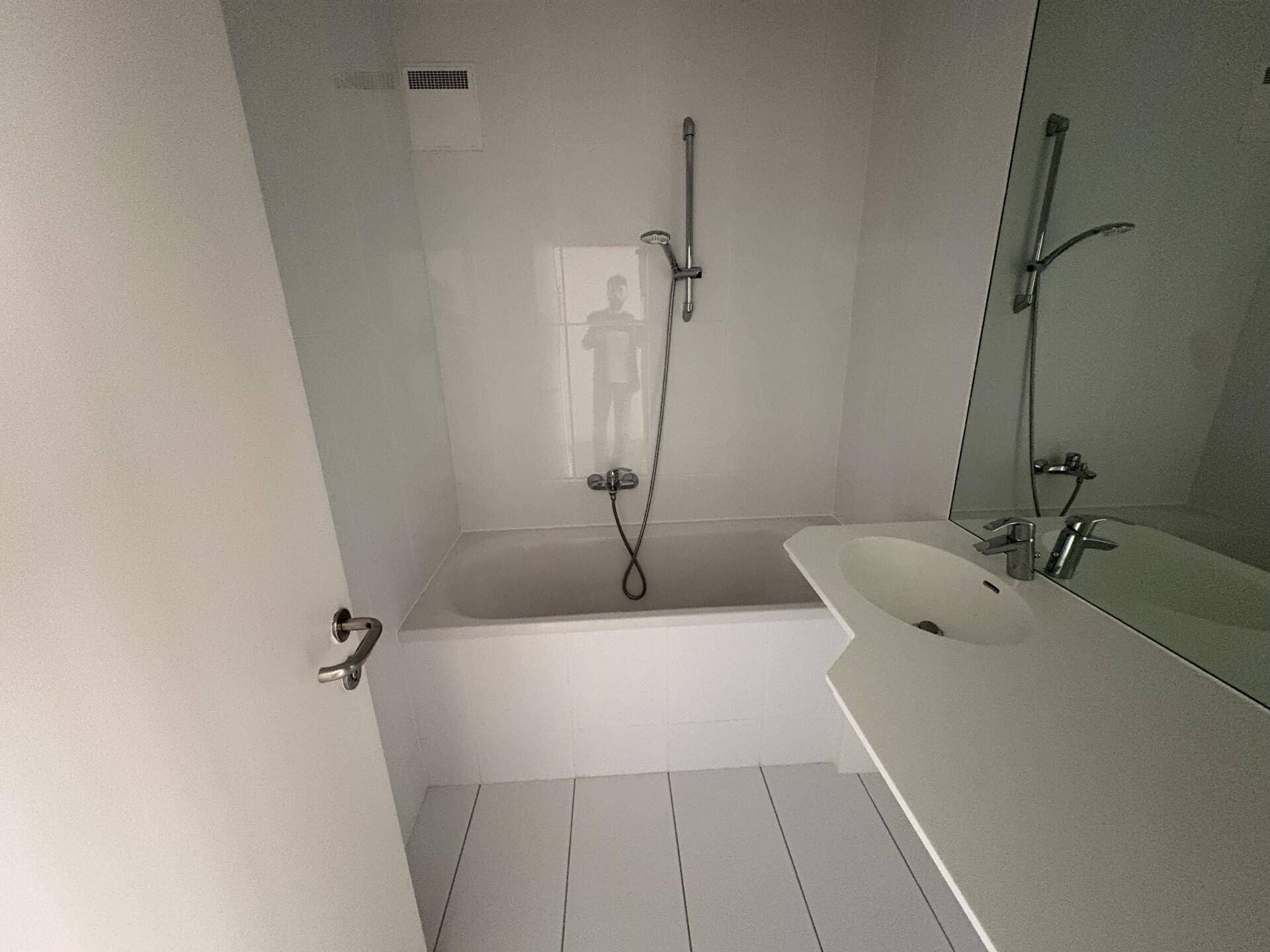 Modernes Badezimmer mit Badewanne, integrierter Dusche und weißem Fliesenboden.