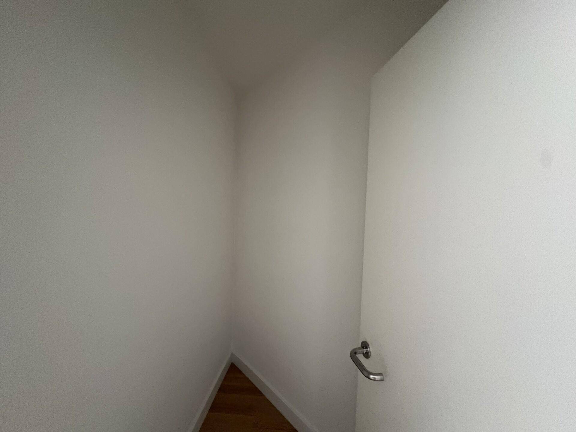 Kleiner Abstellraum oder Nische mit Parkettboden und weißen Wänden.