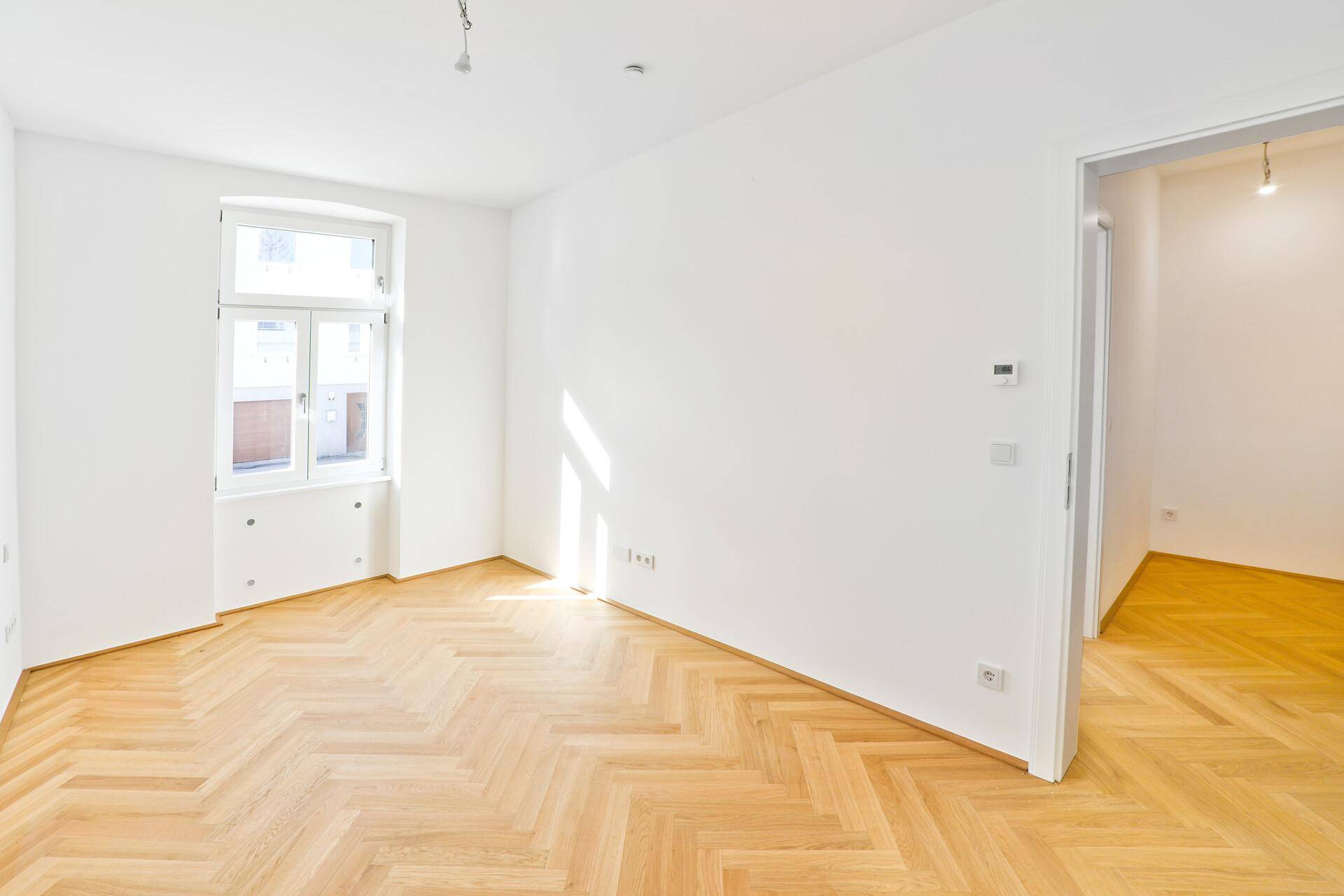 Helles Schlafzimmer mit Fischgrätparkett und weiß gestrichenen Wänden, bereit zum Einrichten.