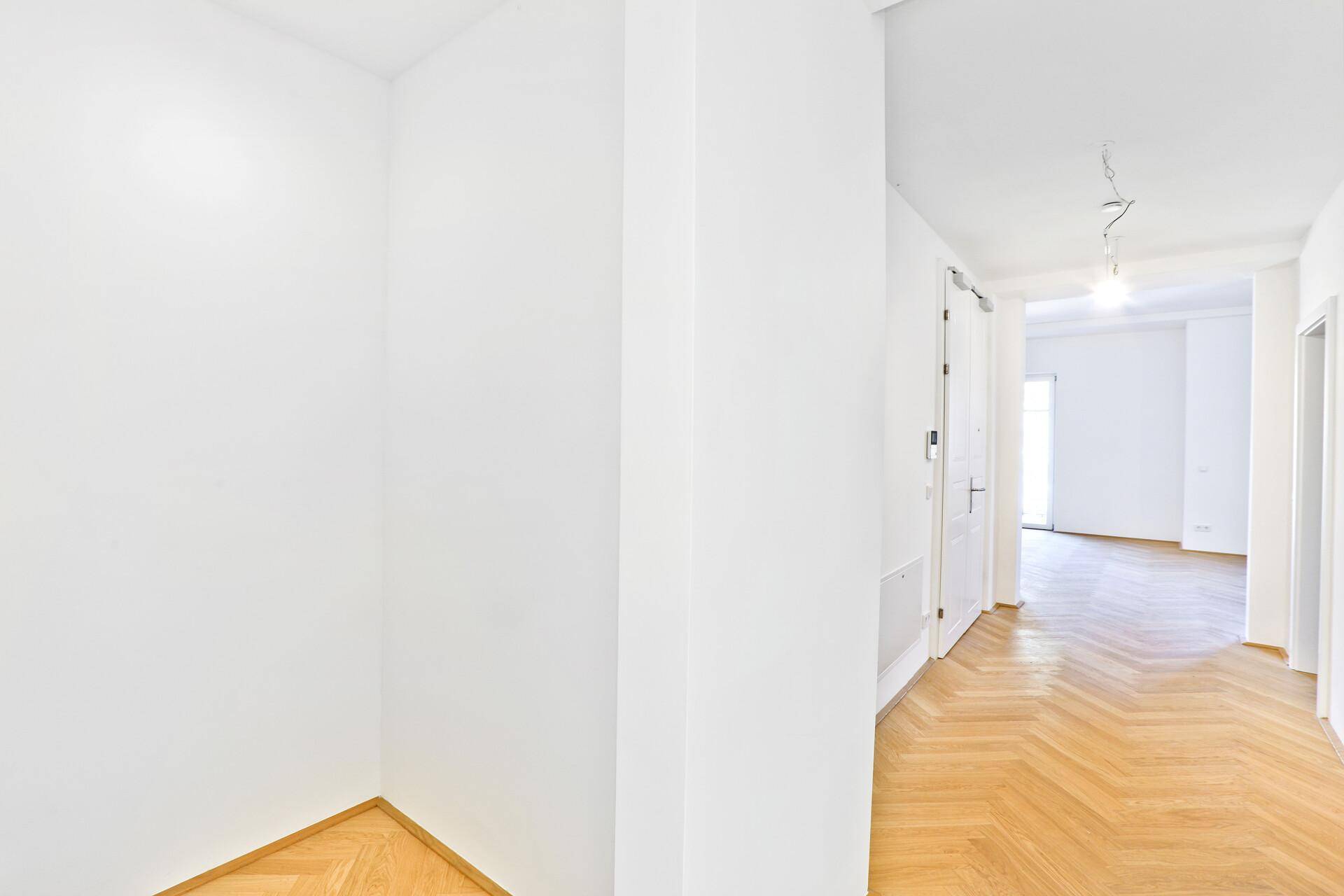 Heller Flur mit elegantem Fischgrätparkett, der zu den verschiedenen Räumen der Wohnung führt.