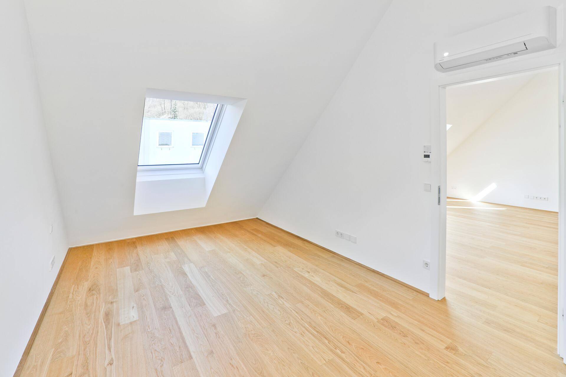 Heller Raum mit Holzparkett, Dachfenster und Klimaanlage, bereit zur individuellen Gestaltung.