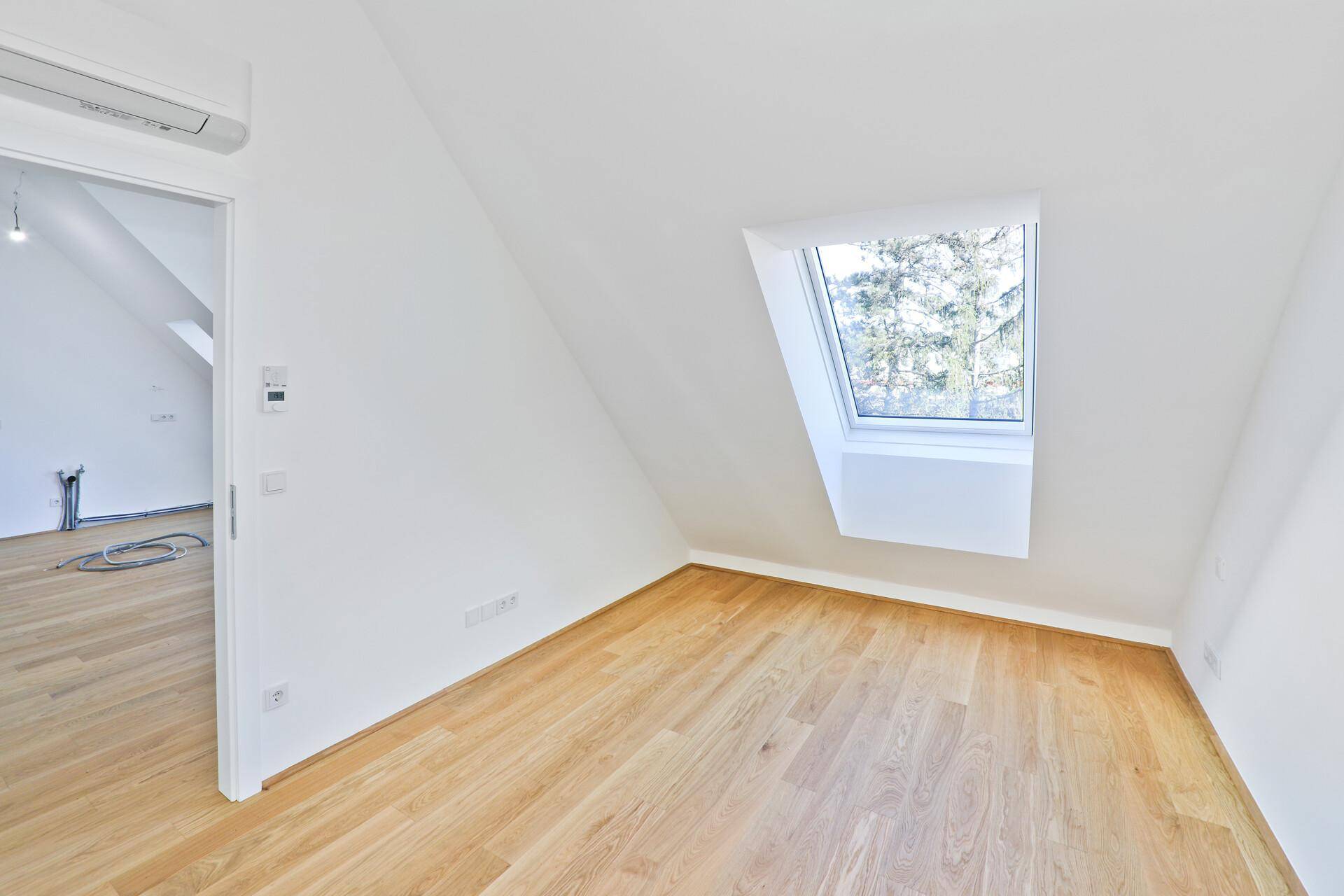 Heller Raum mit Holzparkett, Dachfenster und Dachschräge, ideal als Schlafzimmer.