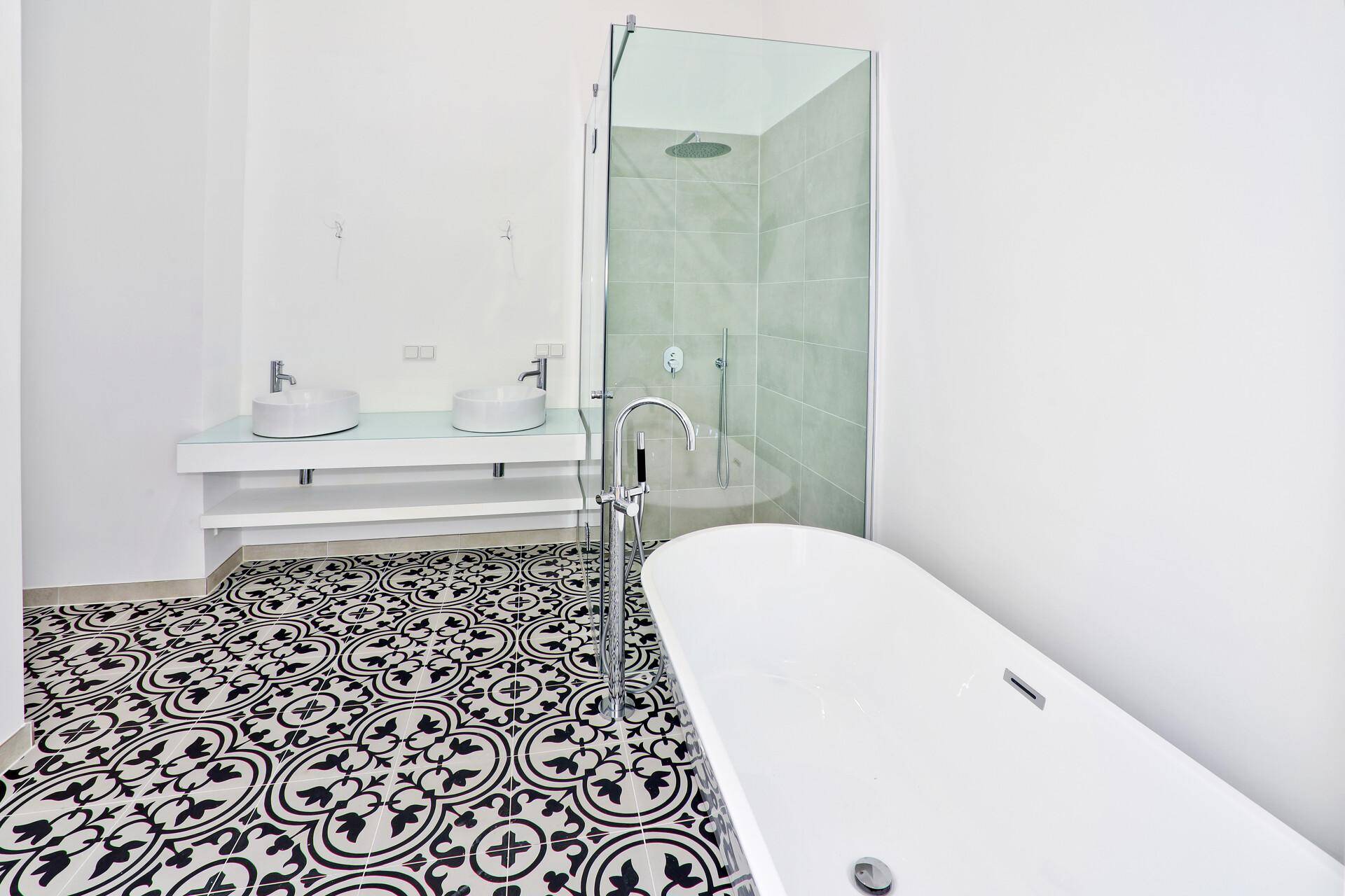 Modernes Badezimmer mit freistehender Badewanne, Doppelwaschbecken und gemusterten Fliesenboden.