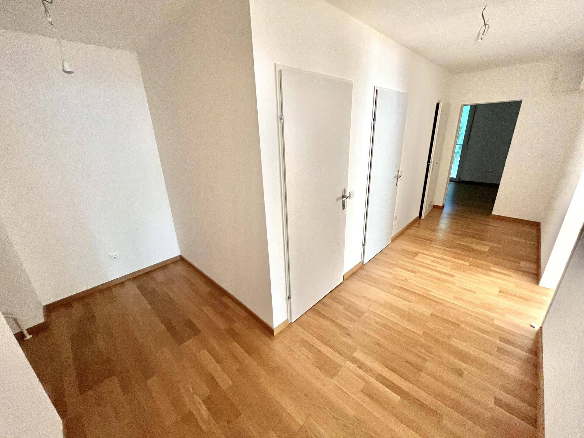 Heller Flurbereich mit Parkettboden und weißen Türen, der zu weiteren Räumen führt.