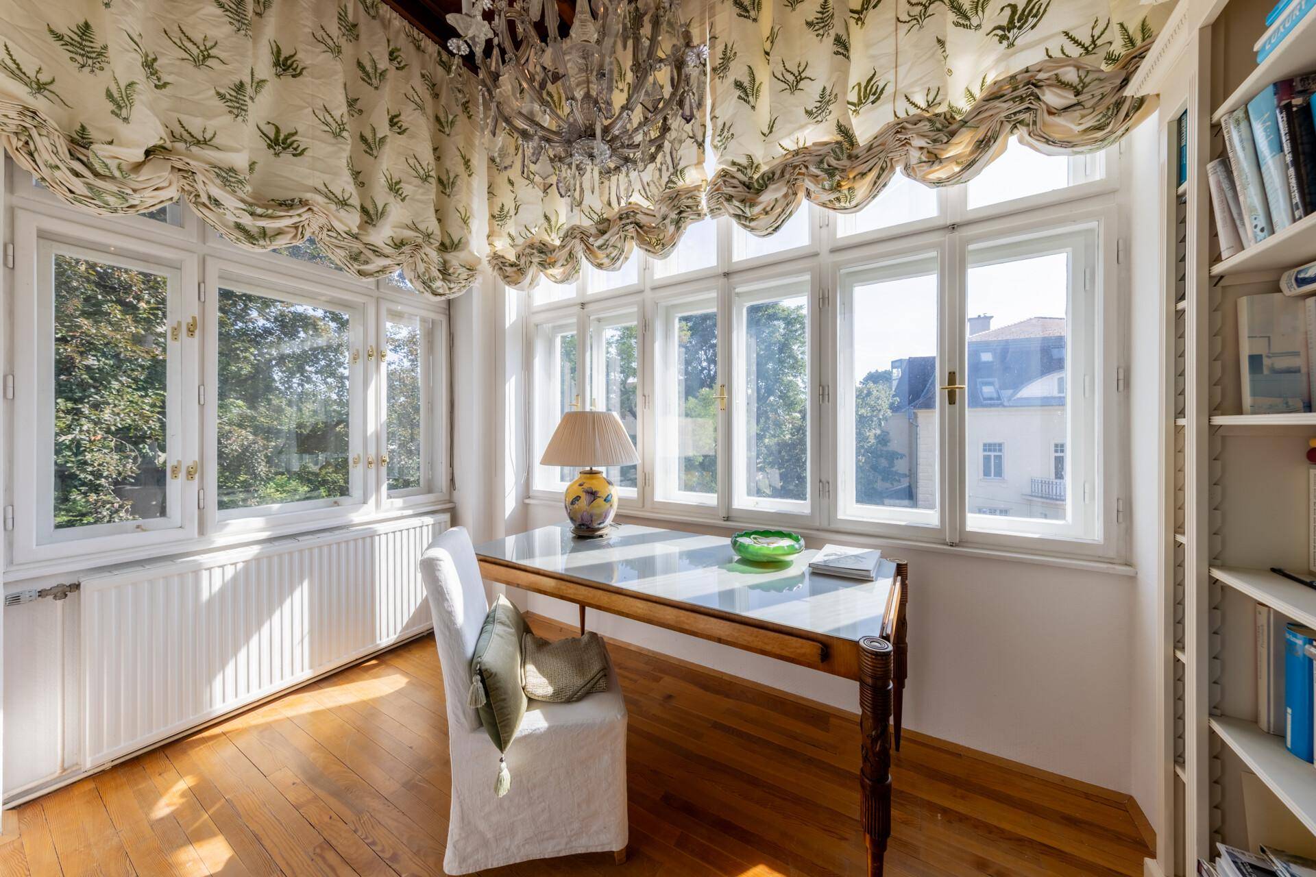 Lichtdurchflutetes Arbeitszimmer mit Holzboden, großem Fenster und Bücherregal.