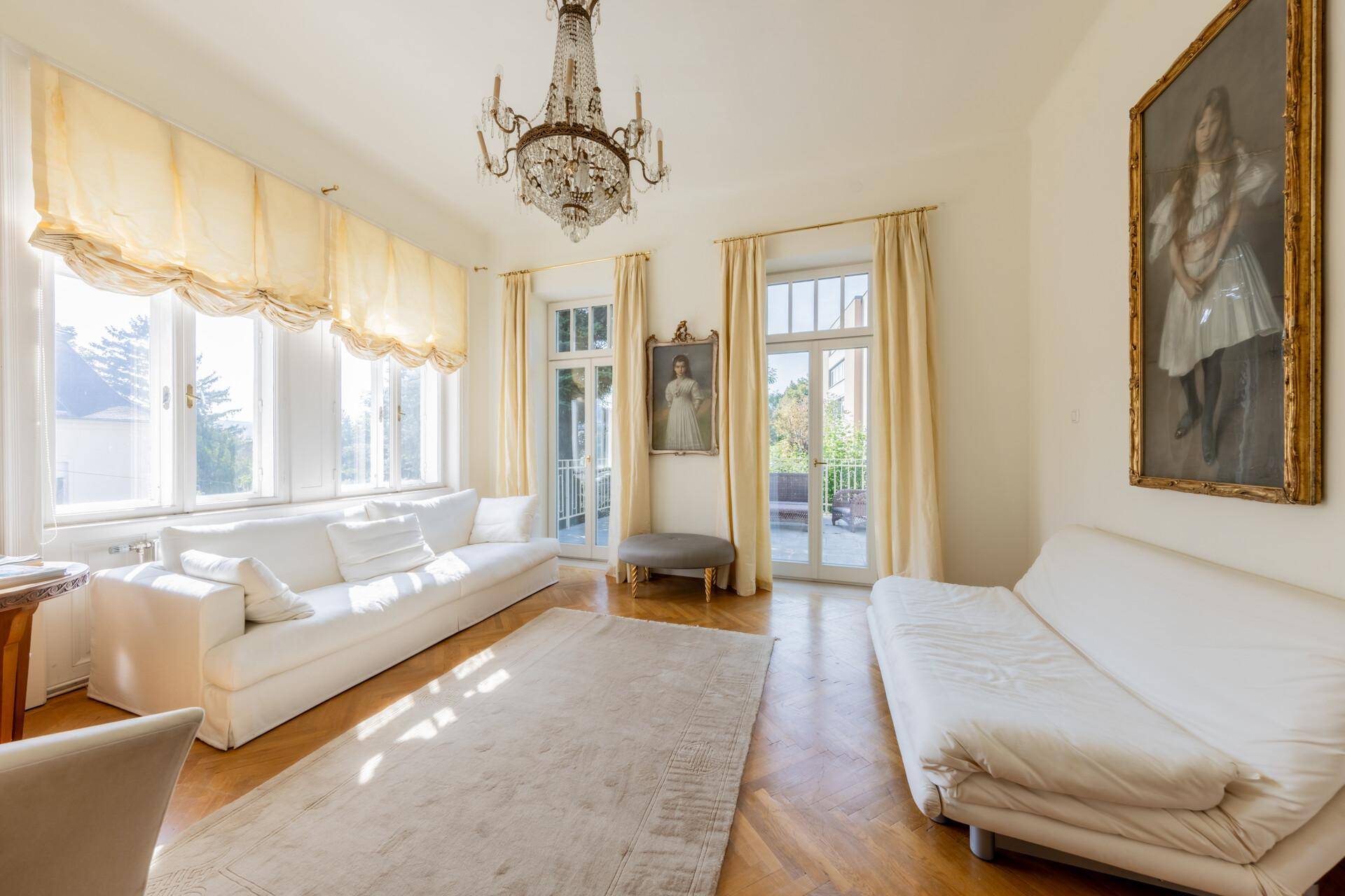 Elegantes Wohnzimmer mit hohen Decken, Parkettboden und Zugang zur Terrasse.