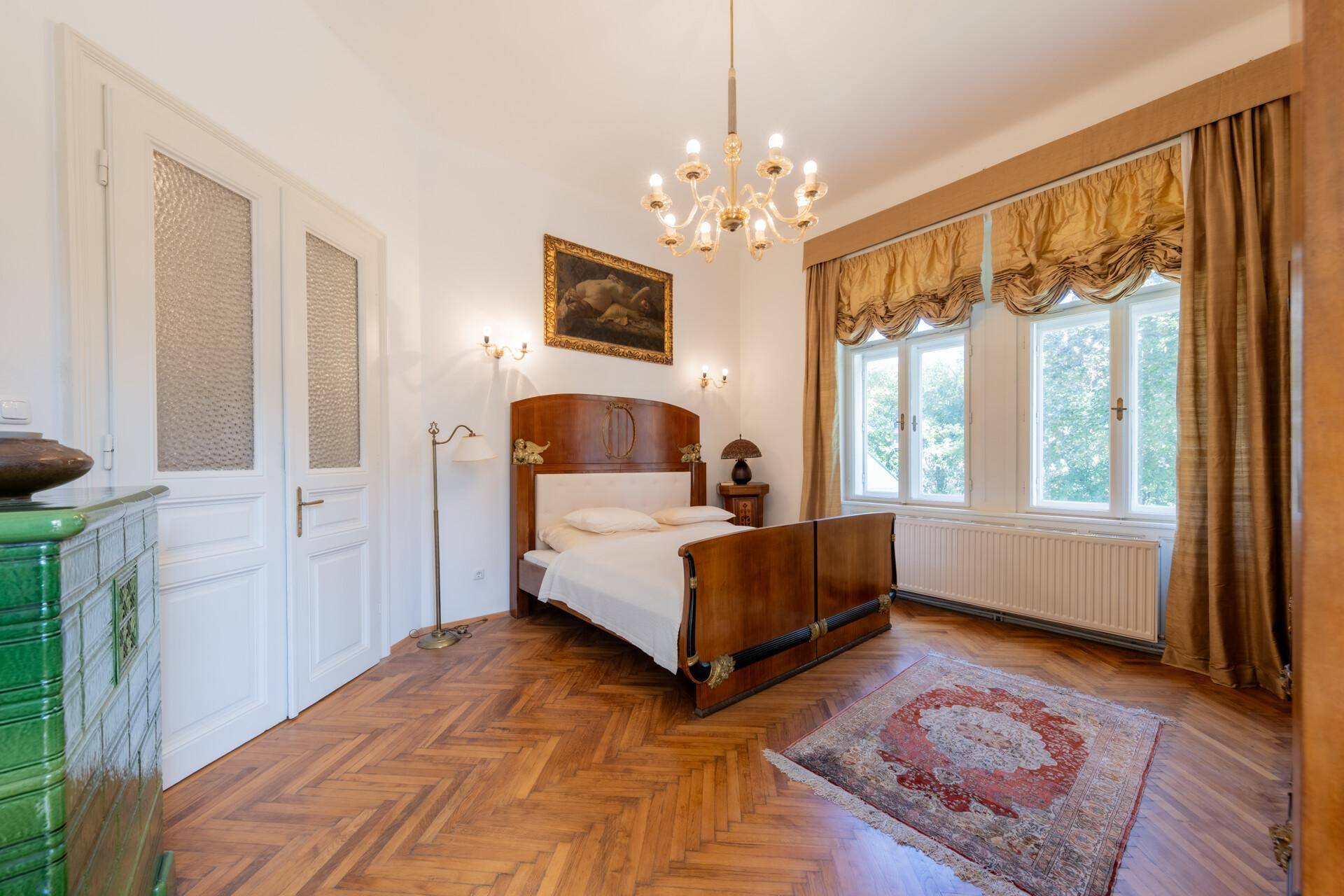 Elegantes Schlafzimmer mit Parkettboden, hohen Decken und großem Fenster.