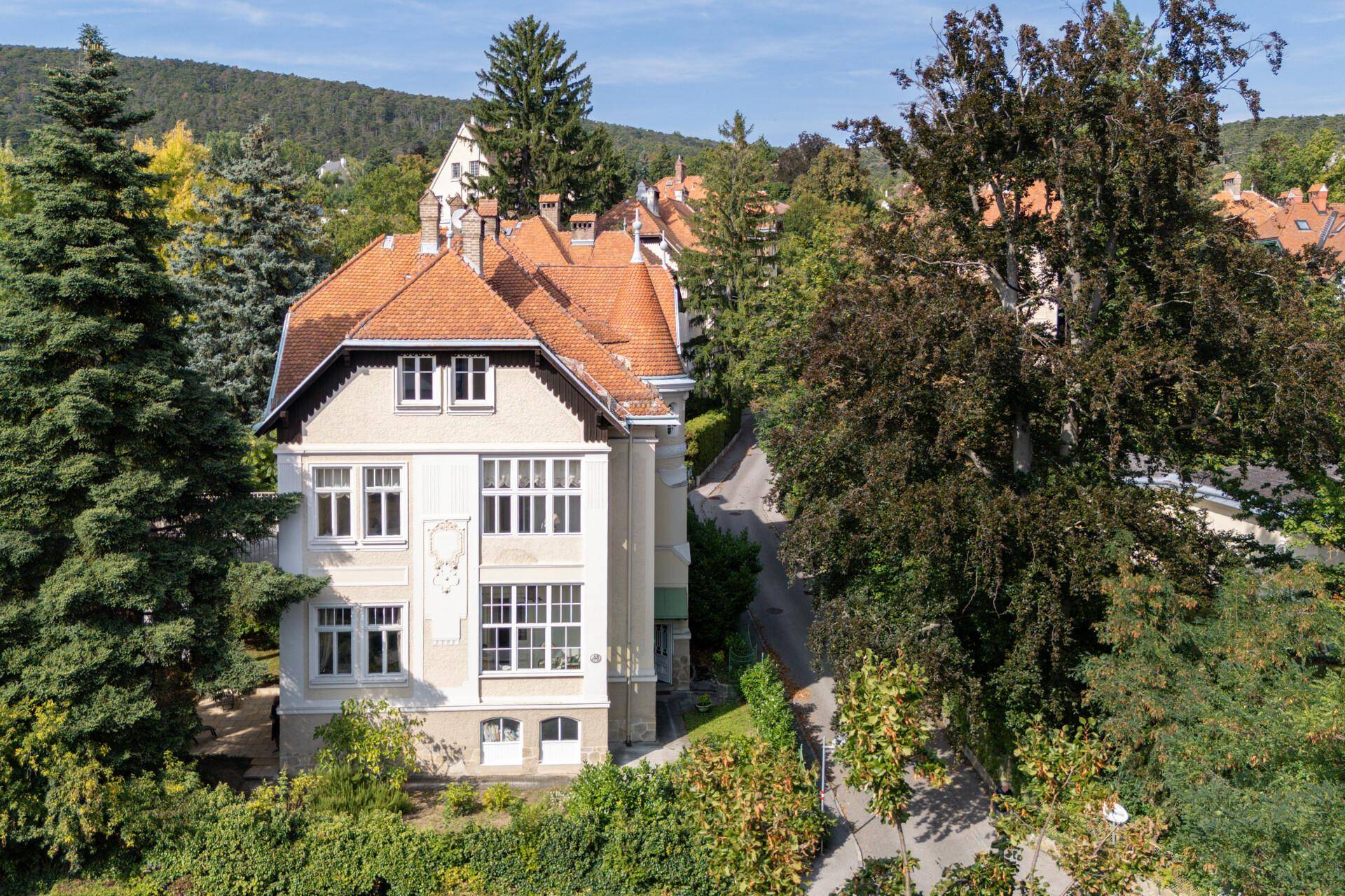 Historische Villa von oben, umgeben von Bäumen und mit Blick auf die Hügellandschaft.