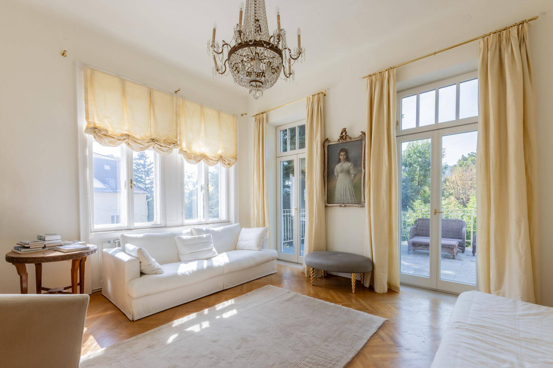 Elegantes Wohnzimmer mit hohen Decken, Parkettboden und Zugang zur Terrasse.