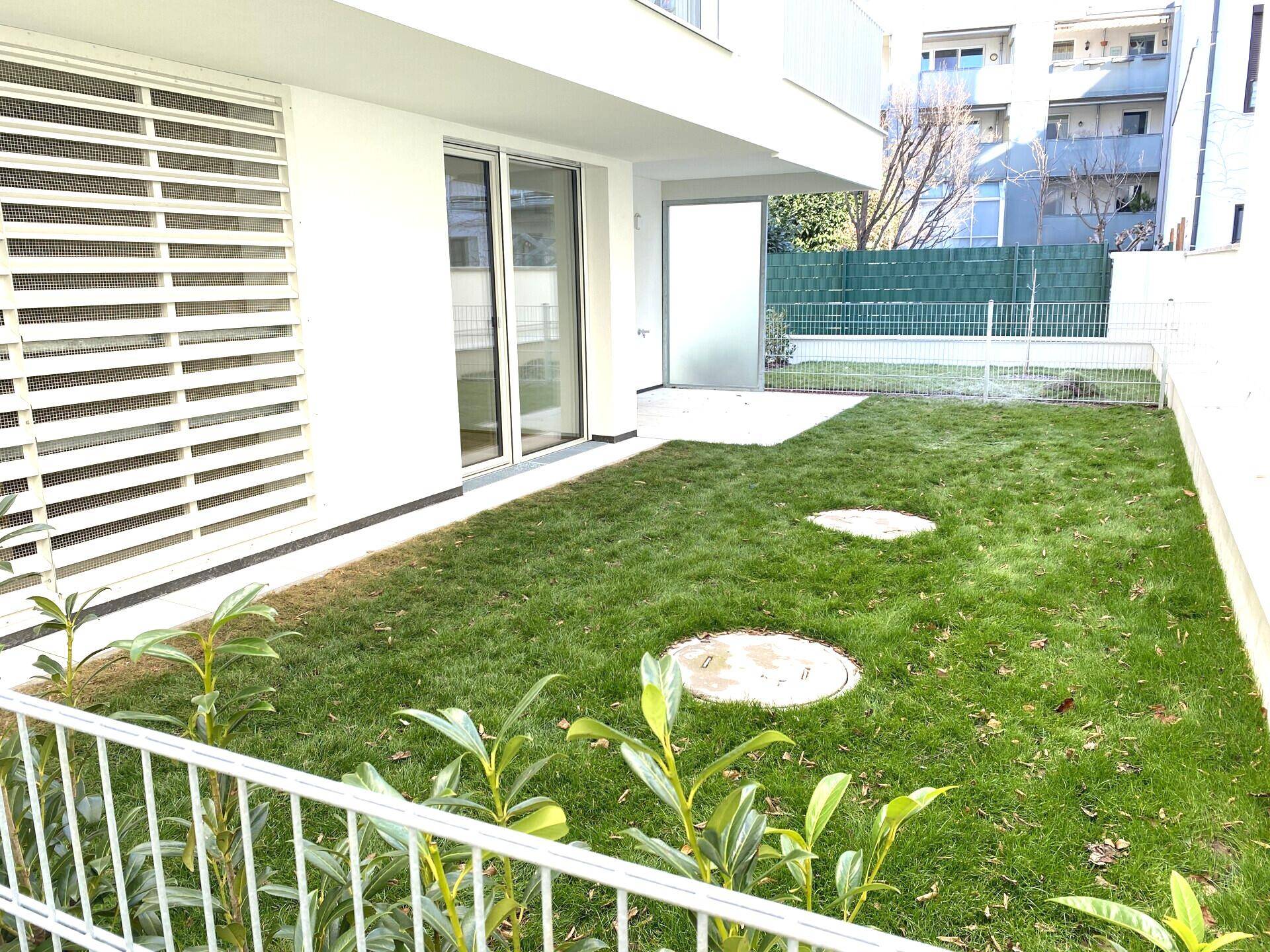 Gepflegter Gartenbereich mit frischem Rasen und einer angrenzenden Terrasse im Erdgeschoss.
