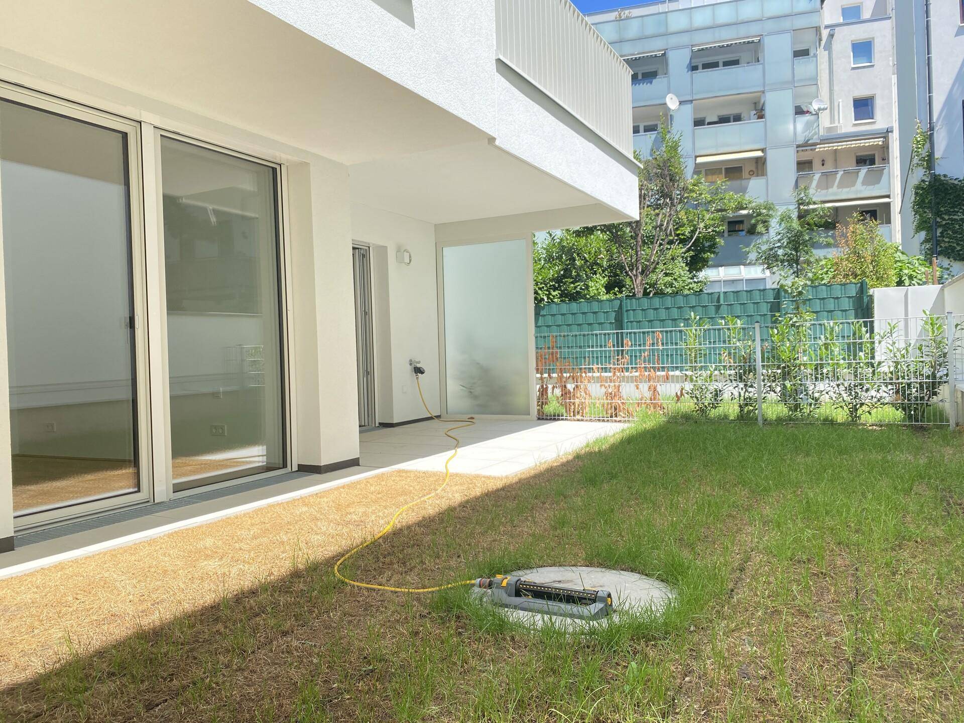 Erdgeschosswohnung mit direktem Zugang zu einem kleinen Garten und einer gepflasterten Terrasse.