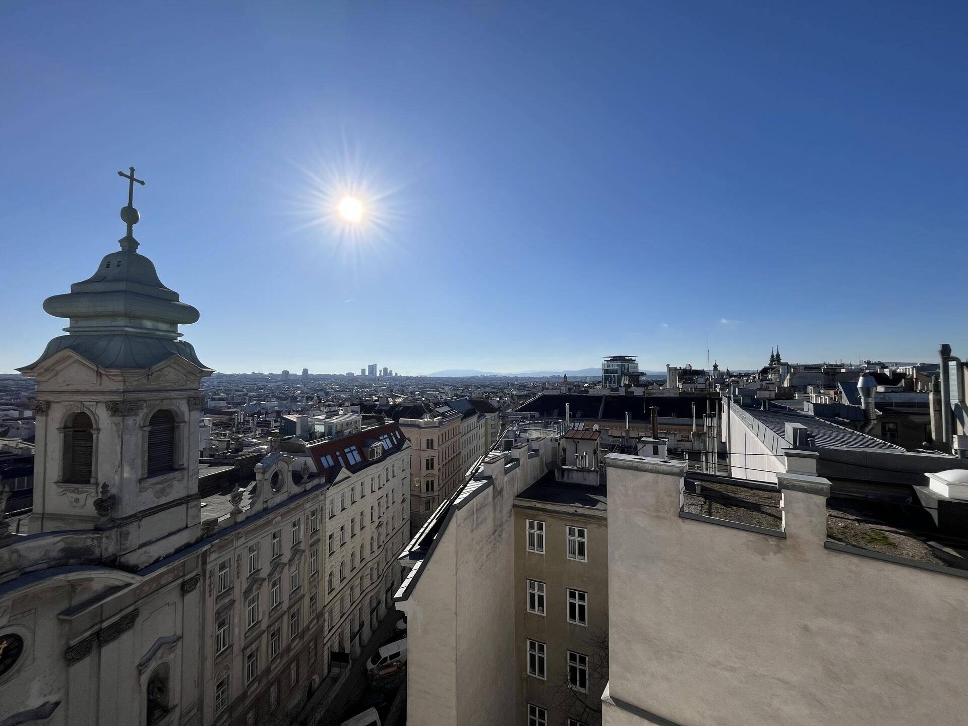 Panoramablick über die Stadt Wien mit historischer Kirche und sonnigem Himmel.