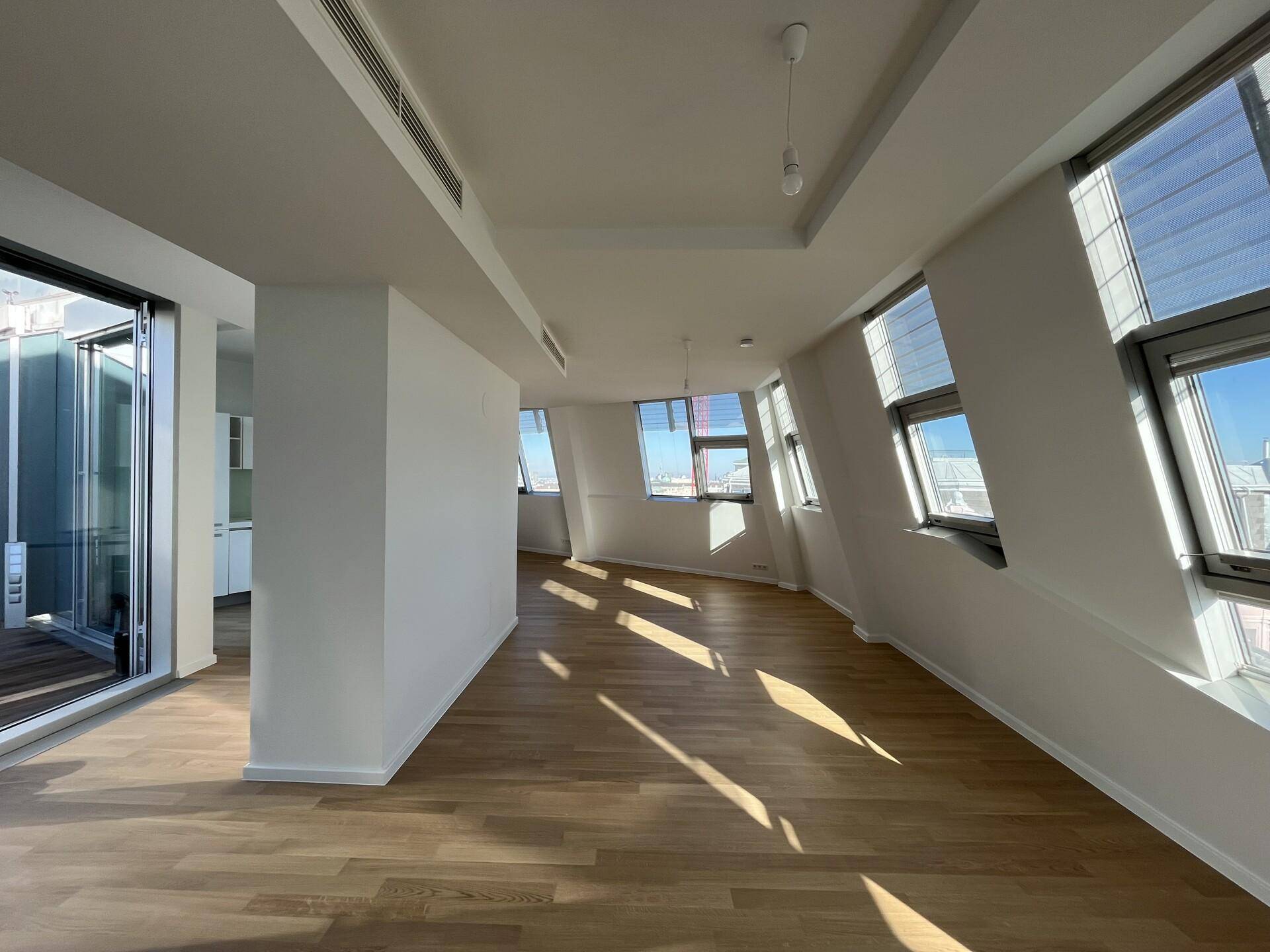 Geräumiger, lichtdurchfluteter Wohnbereich mit Holzboden und schrägen Dachfenstern.