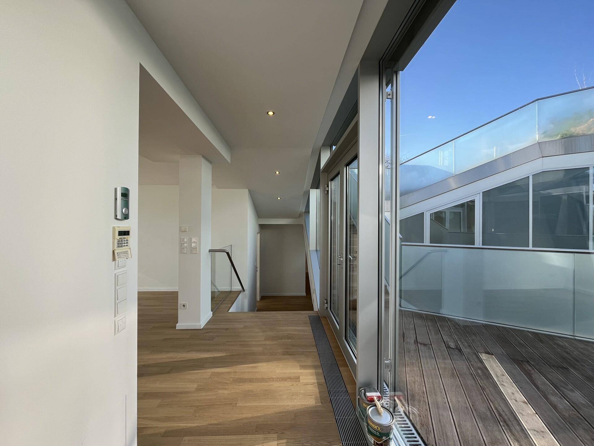 Heller Eingangsbereich mit Holzboden und großen Glasfronten, die zur Terrasse führen.