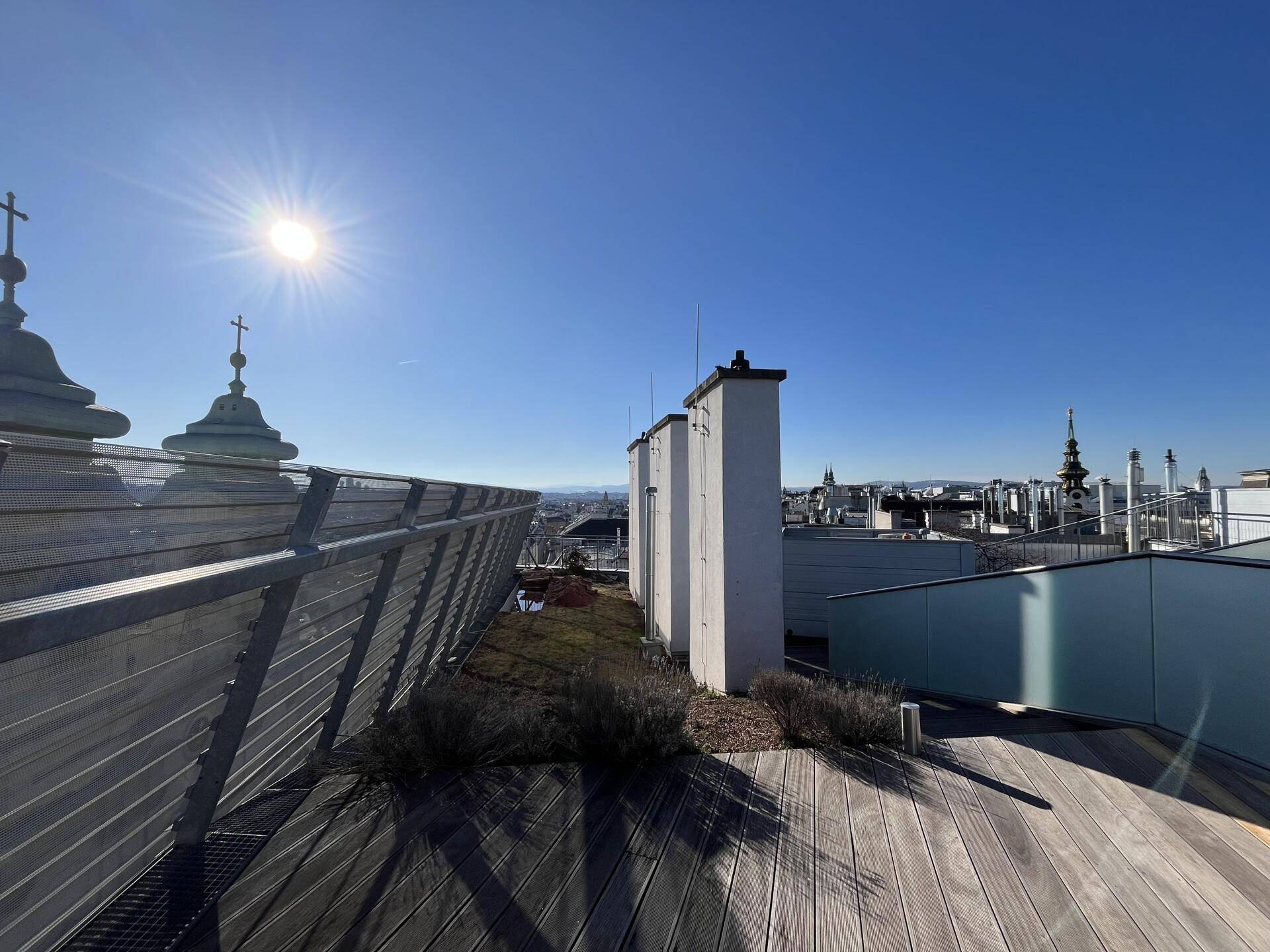 Weitläufige Dachterrasse mit Holzboden und Panoramablick über die Stadt.
