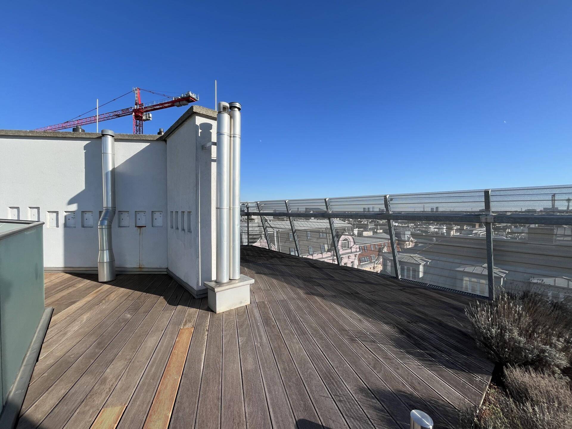 Dachterrasse mit Holzboden und weitem Blick über die Dächer der Stadt.