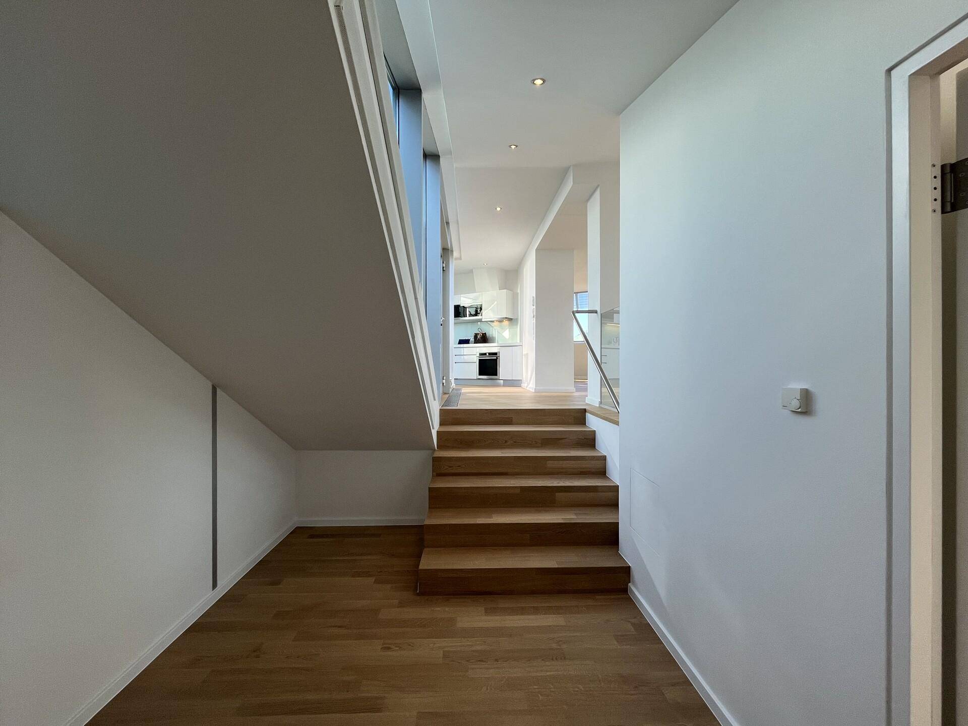 Moderner Treppenaufgang mit Holzboden, der verschiedene Ebenen der Wohnung verbindet.