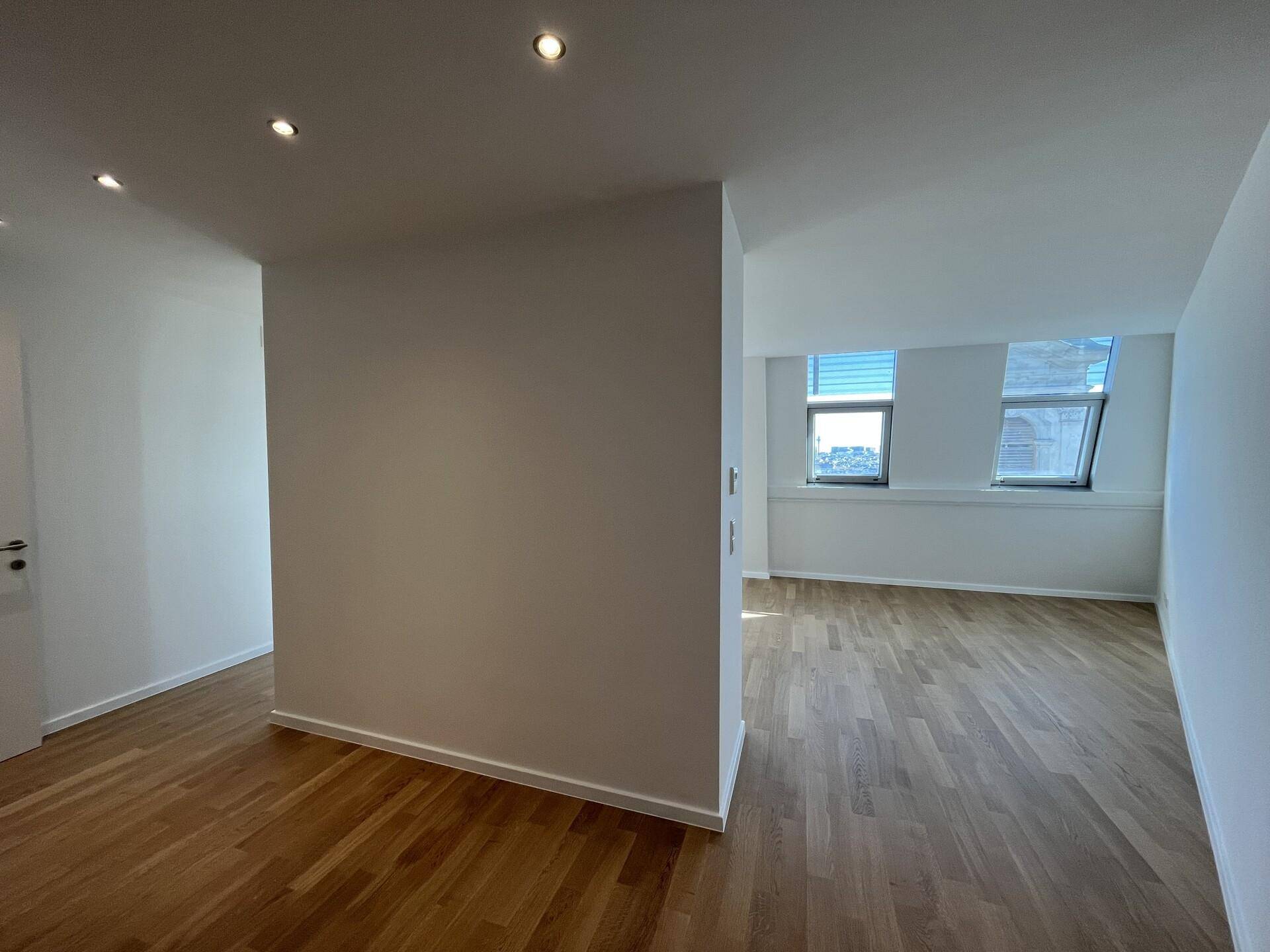 Heller Raum mit Holzboden und Einbaustrahlern, der flexibel genutzt werden kann.